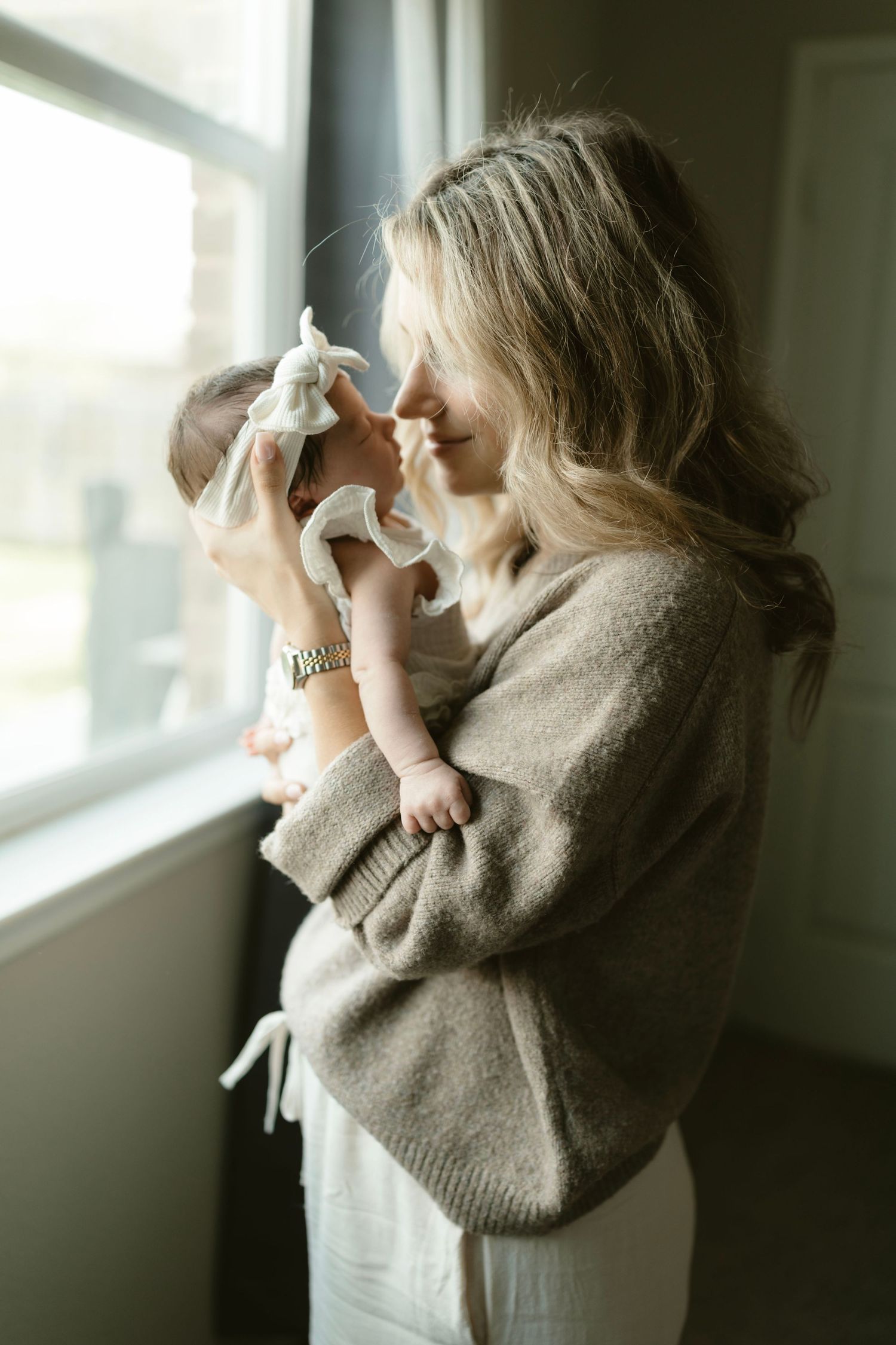 A mom holding her baby nose to nose, standing by a window