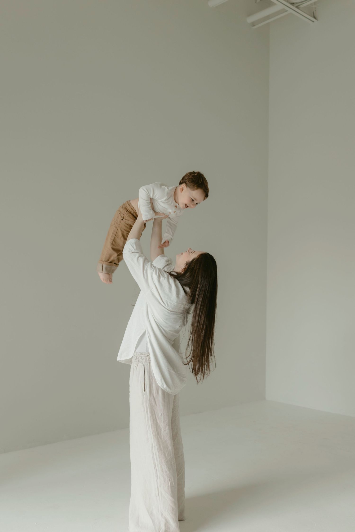 Motherhood session of a mom playing with her son in a minimalist white studio in Central Texas.