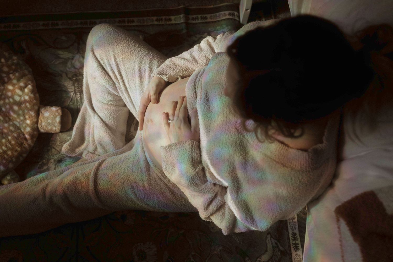 An expectant mother holding her belly, sitting on the floor