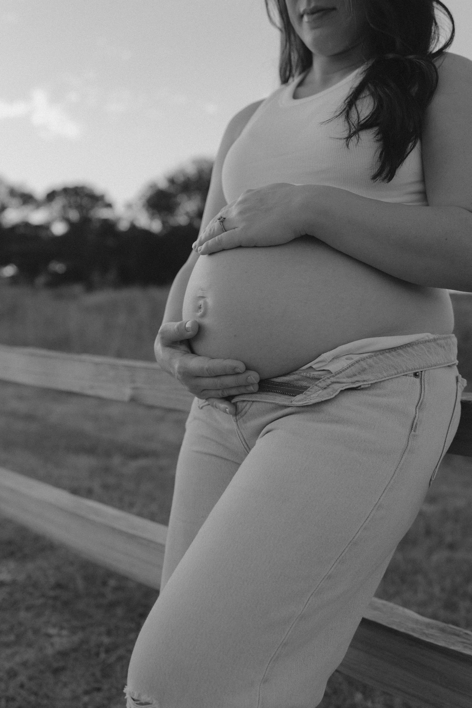 Black and white maternity portraits showing pregnant belly against outdoor backdrop.