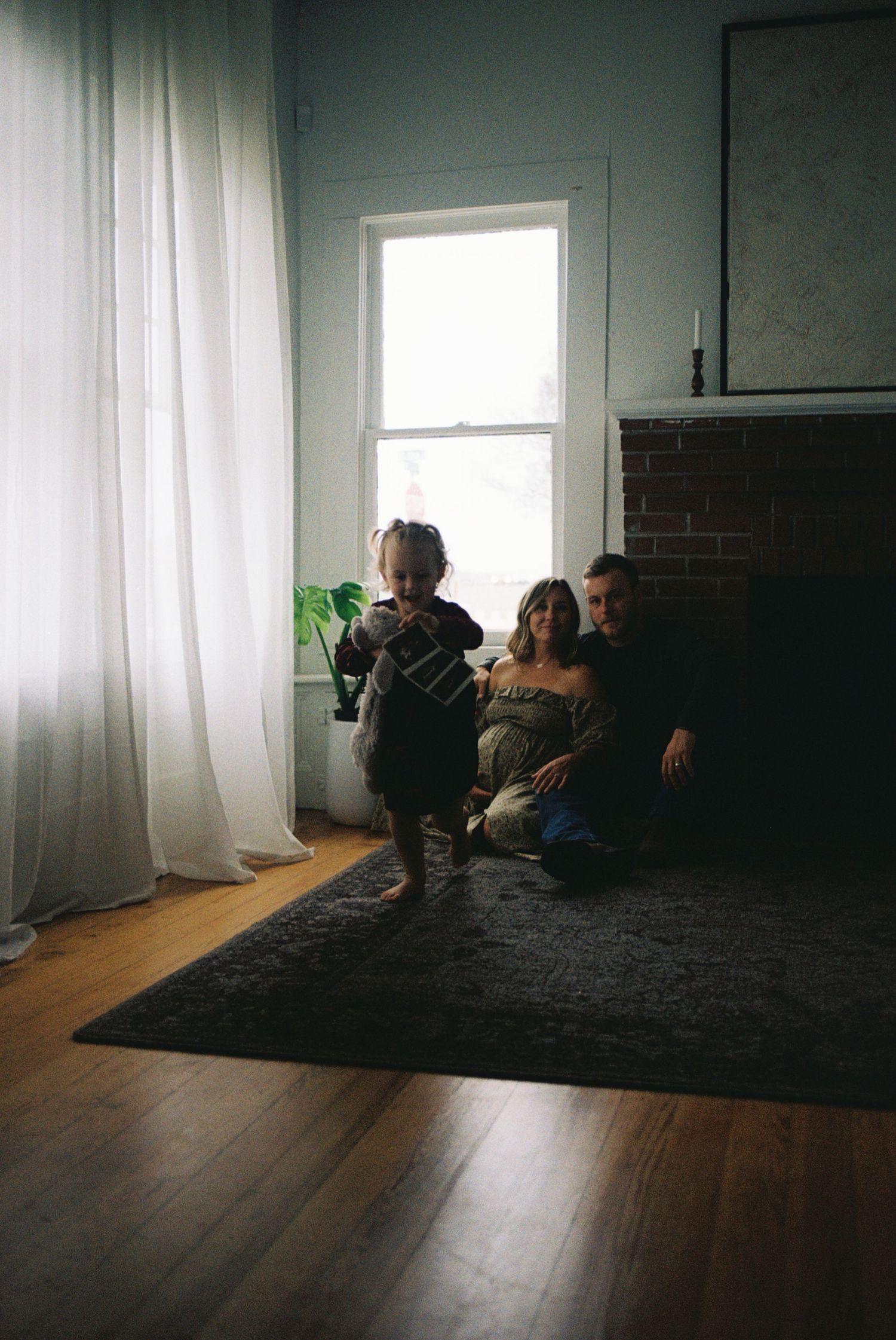 A dark moody room with hardwood floors and white curtains shown in four sequential photos with changing light.