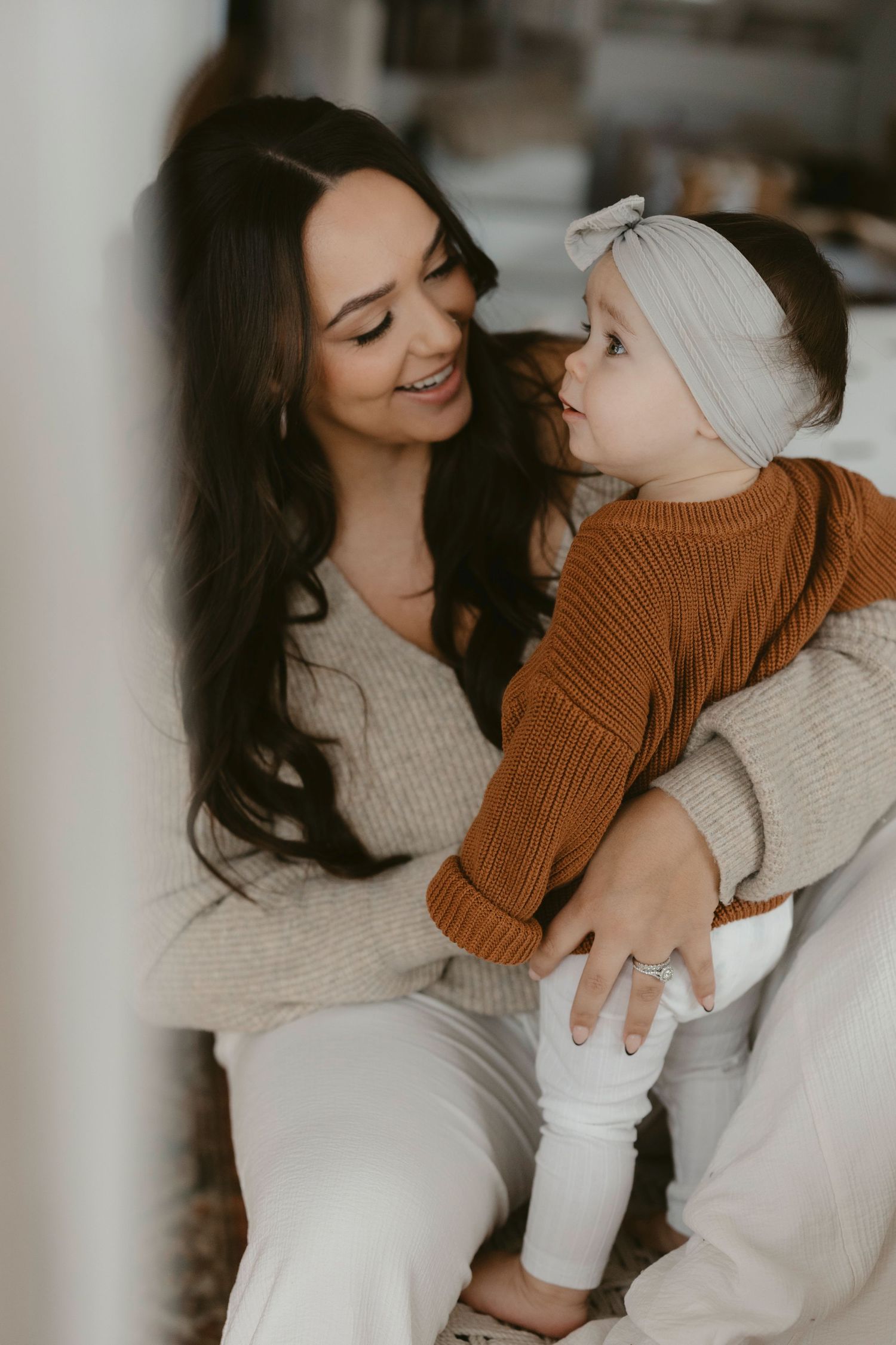 Cozy indoor portrait of parent and baby in matching neutral sweaters.