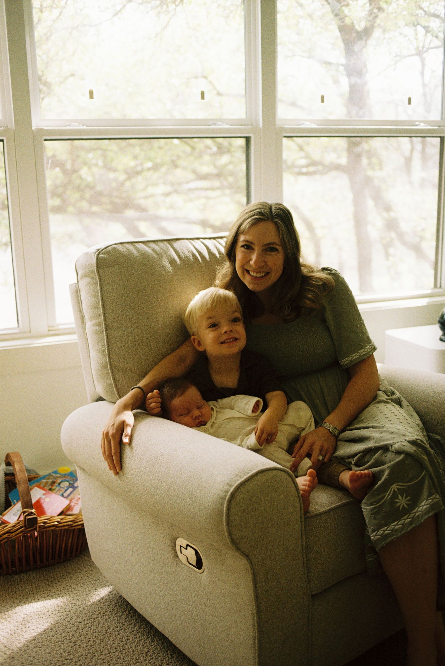 A relaxing scene shows a cozy grey recliner by large windows where adults and children lounge together.