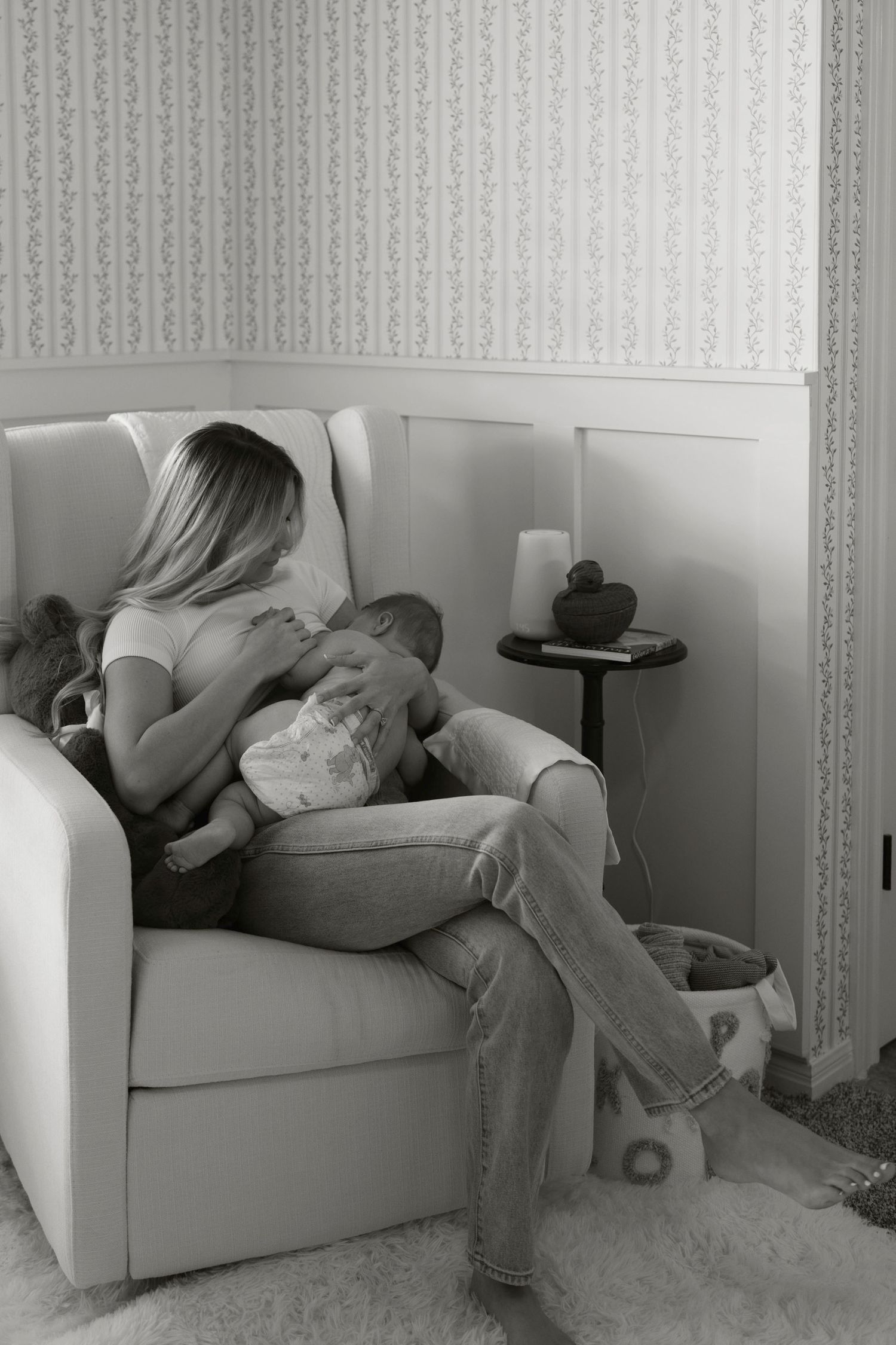 A series of four black and white photos In-home motherhood session capturing a mom breastfeeding her baby in soft light.