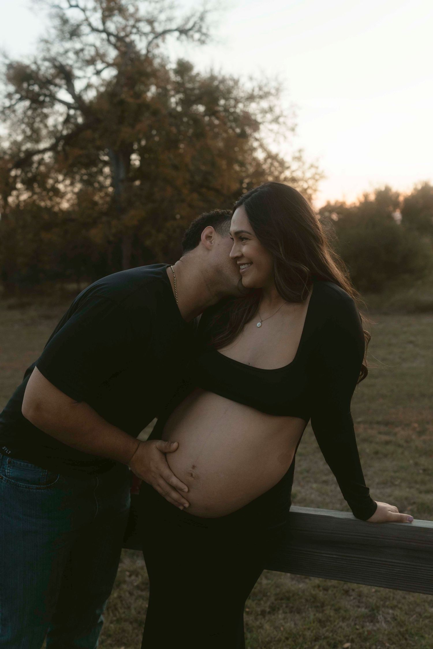 Intimate maternity photo session showing tender moments between couple in an outdoor setting at dusk.