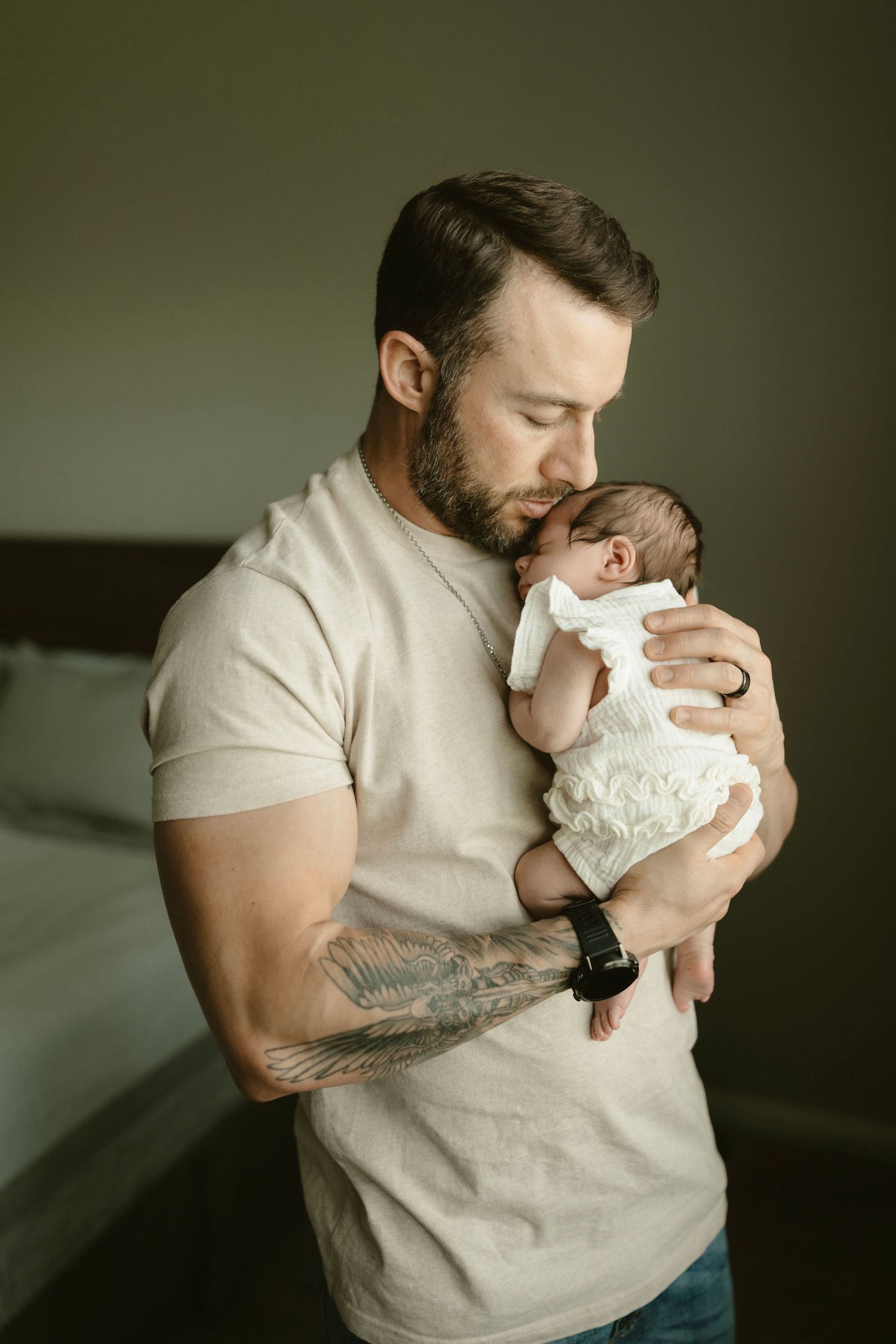 Father in cream shirt holding sleeping newborn during photography session with Brittany Ruiz Photography.
