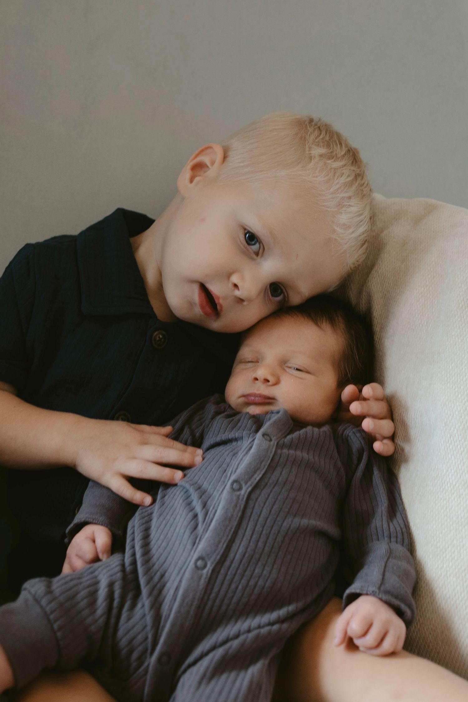 Moody portrait of baby brother holding his newborn sibling