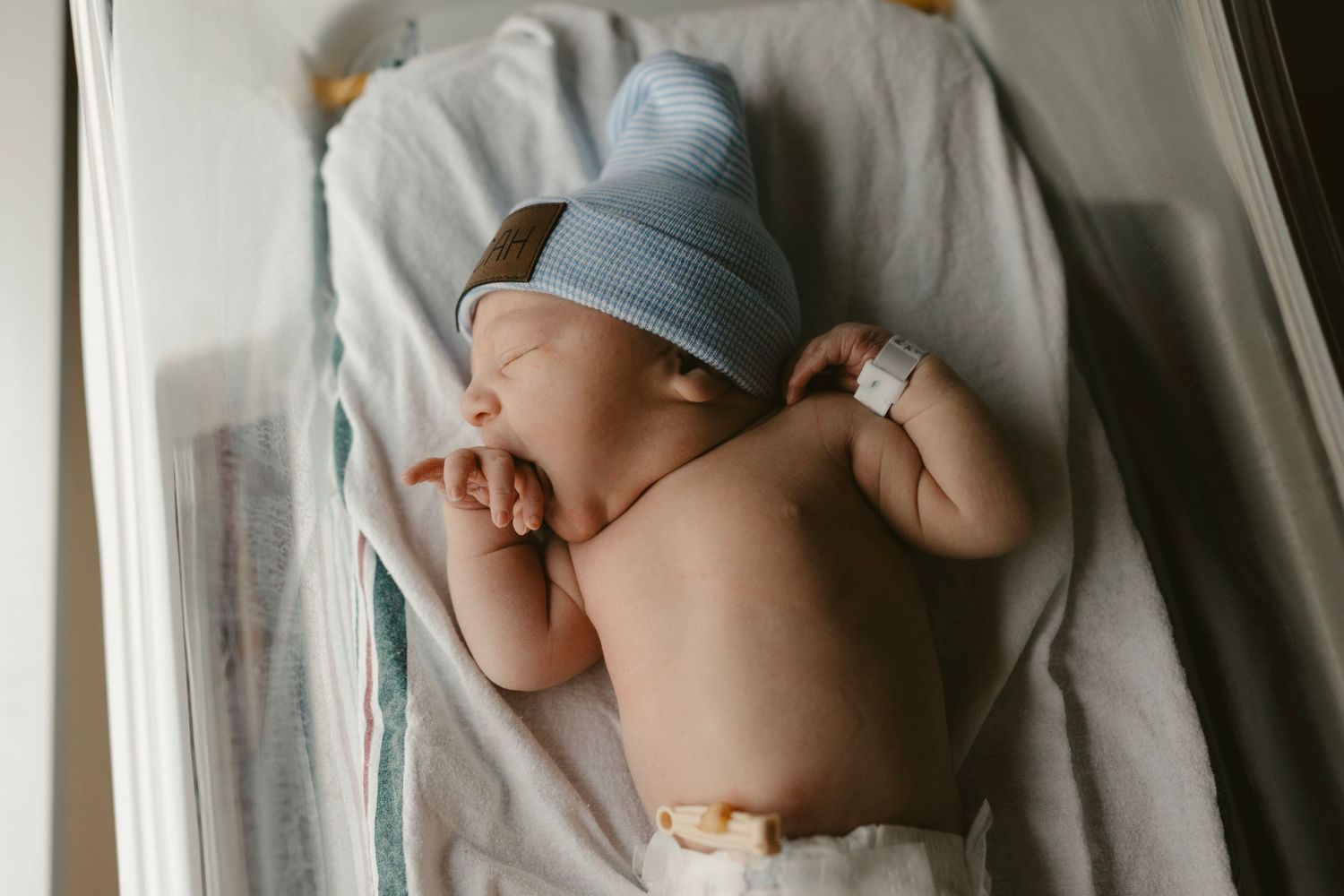 Side view of sleeping newborn in blue hat.