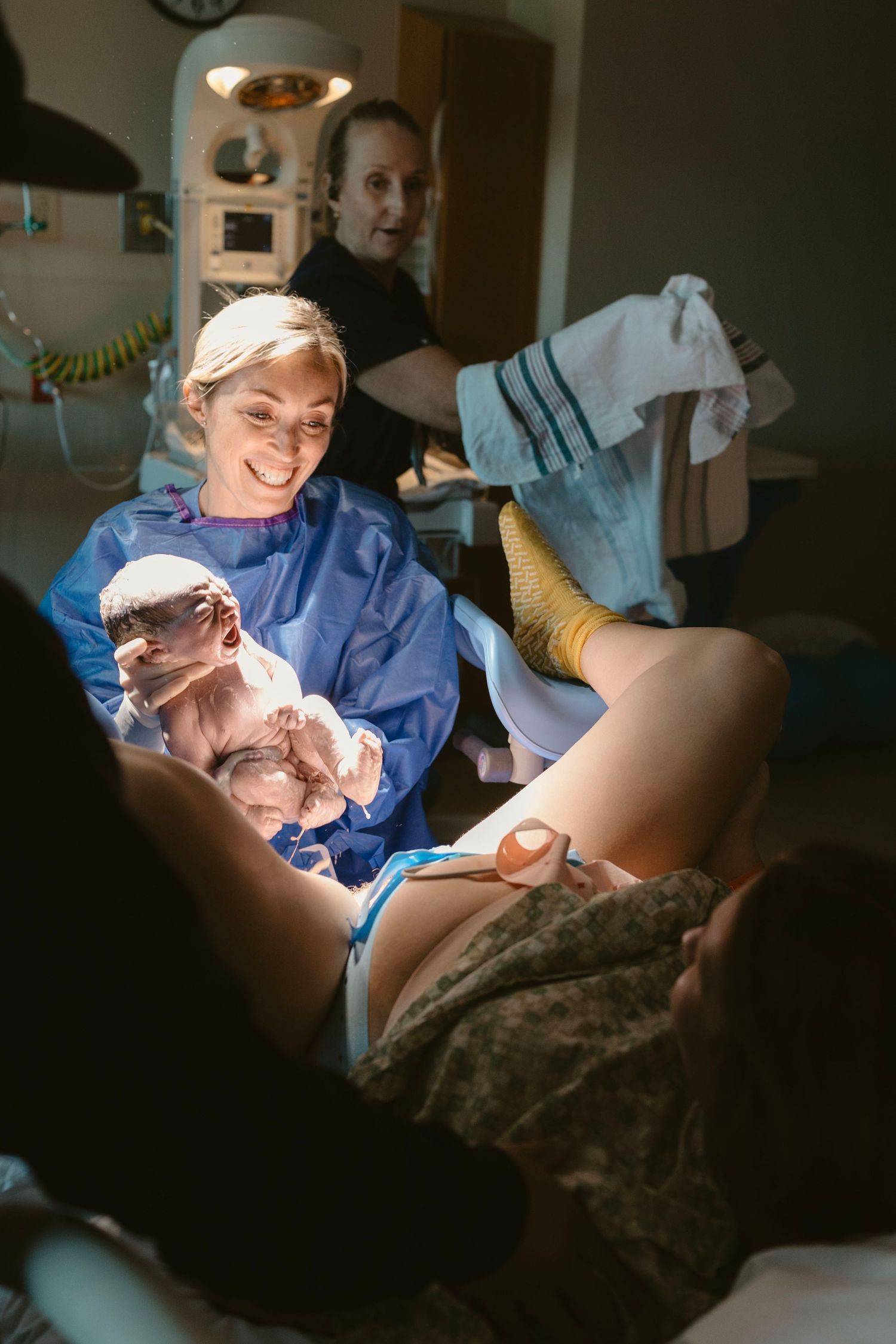 Emotional birth image of a mother supported during active labor as her baby is born.