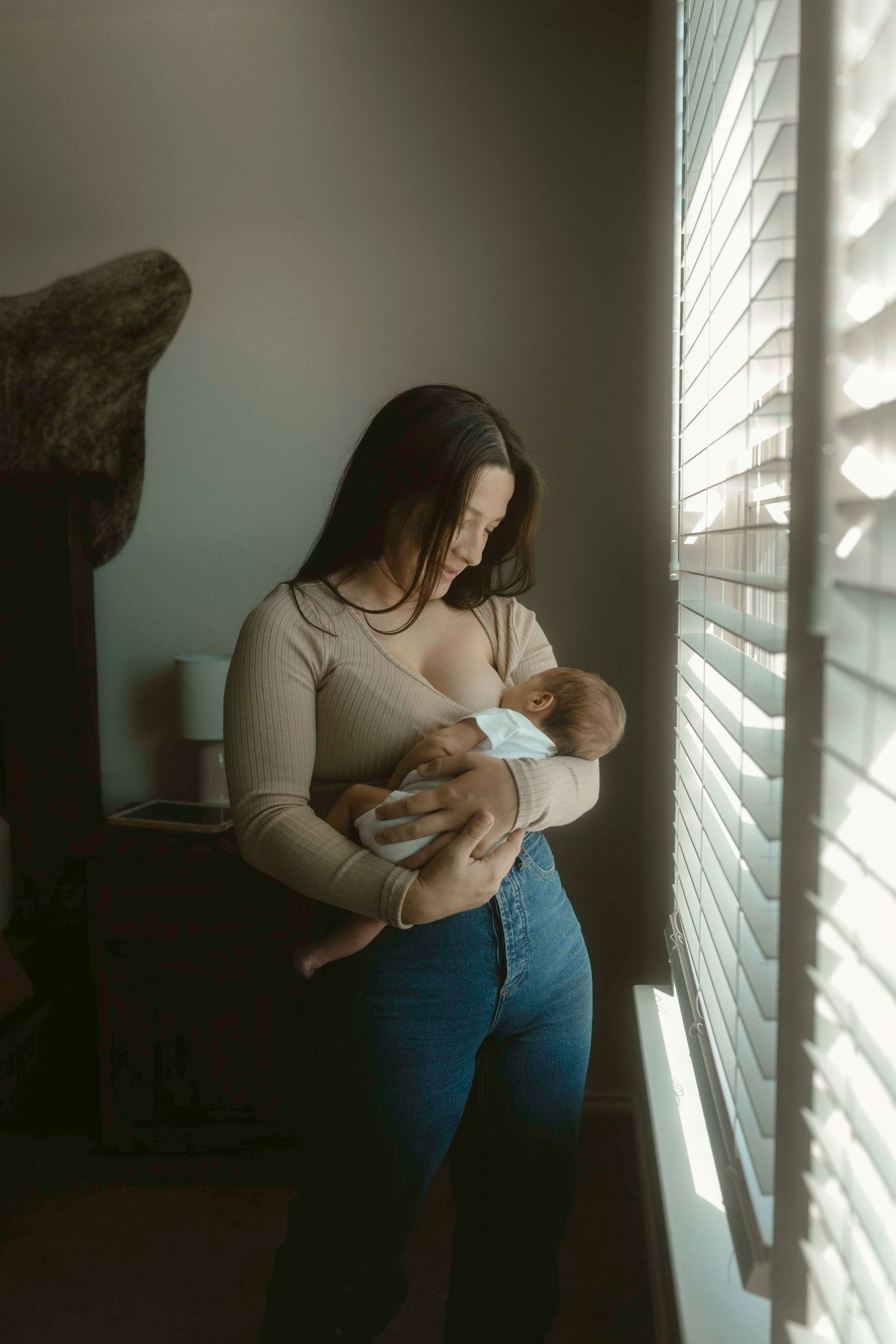 A series of intimate indoor portraits showing tender moments between mom and baby in soft window light.