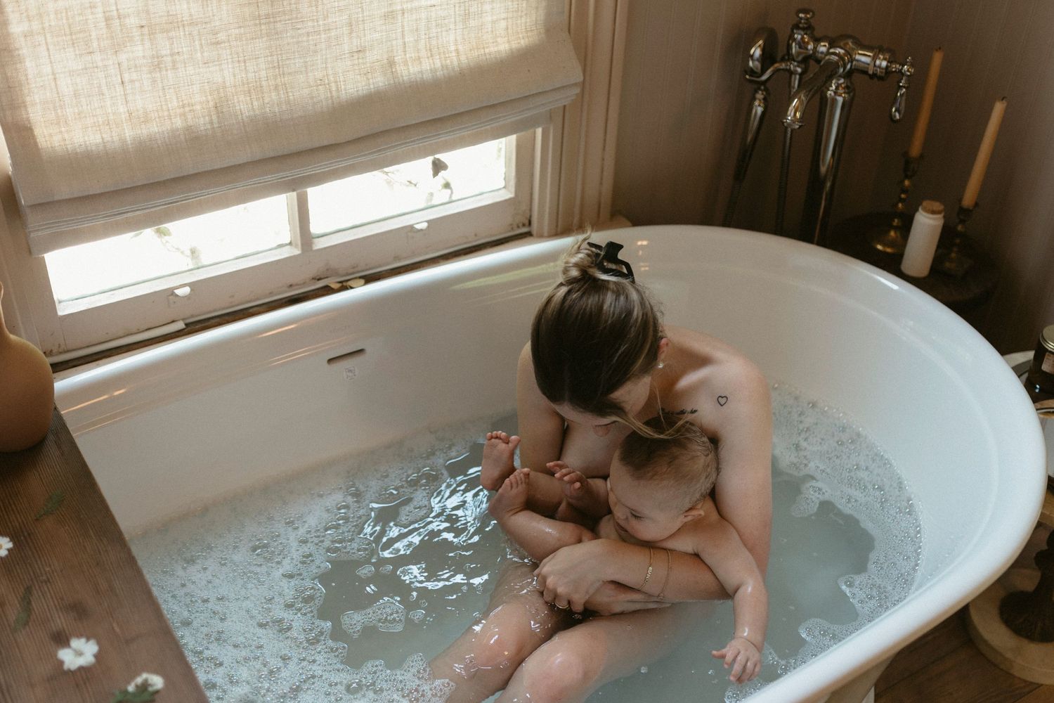 Intimate bathing moment between mother and baby captured in clawfoot tub with natural light by Brittany Ruiz Photography in Austin, TX.