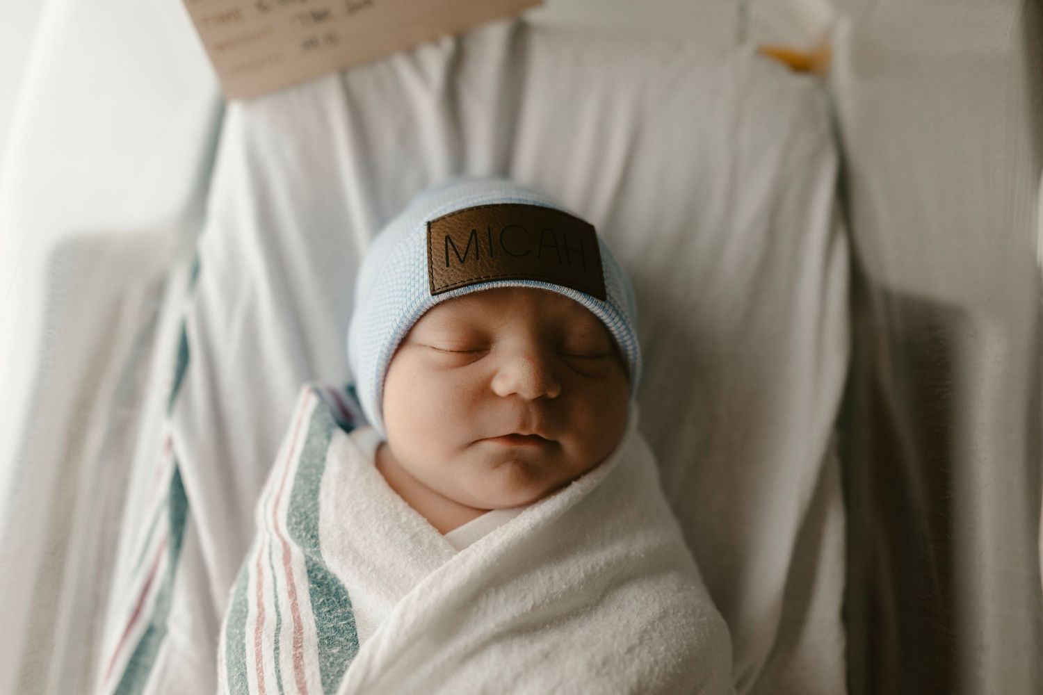 Image of peaceful newborn baby sleeping soundly in white swaddle.