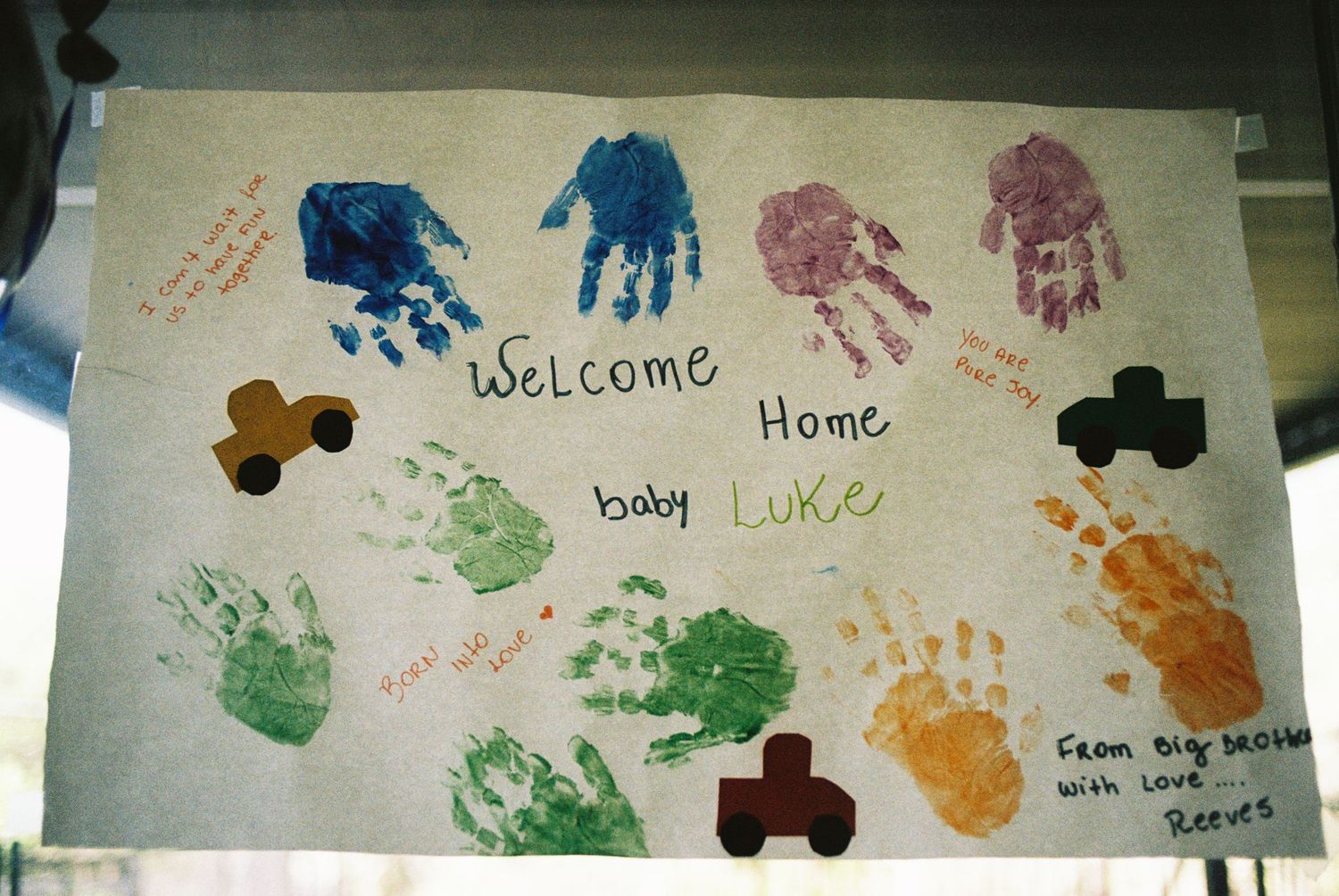 Colorful handprints and footprints decorate a welcome home banner with painted decorations.