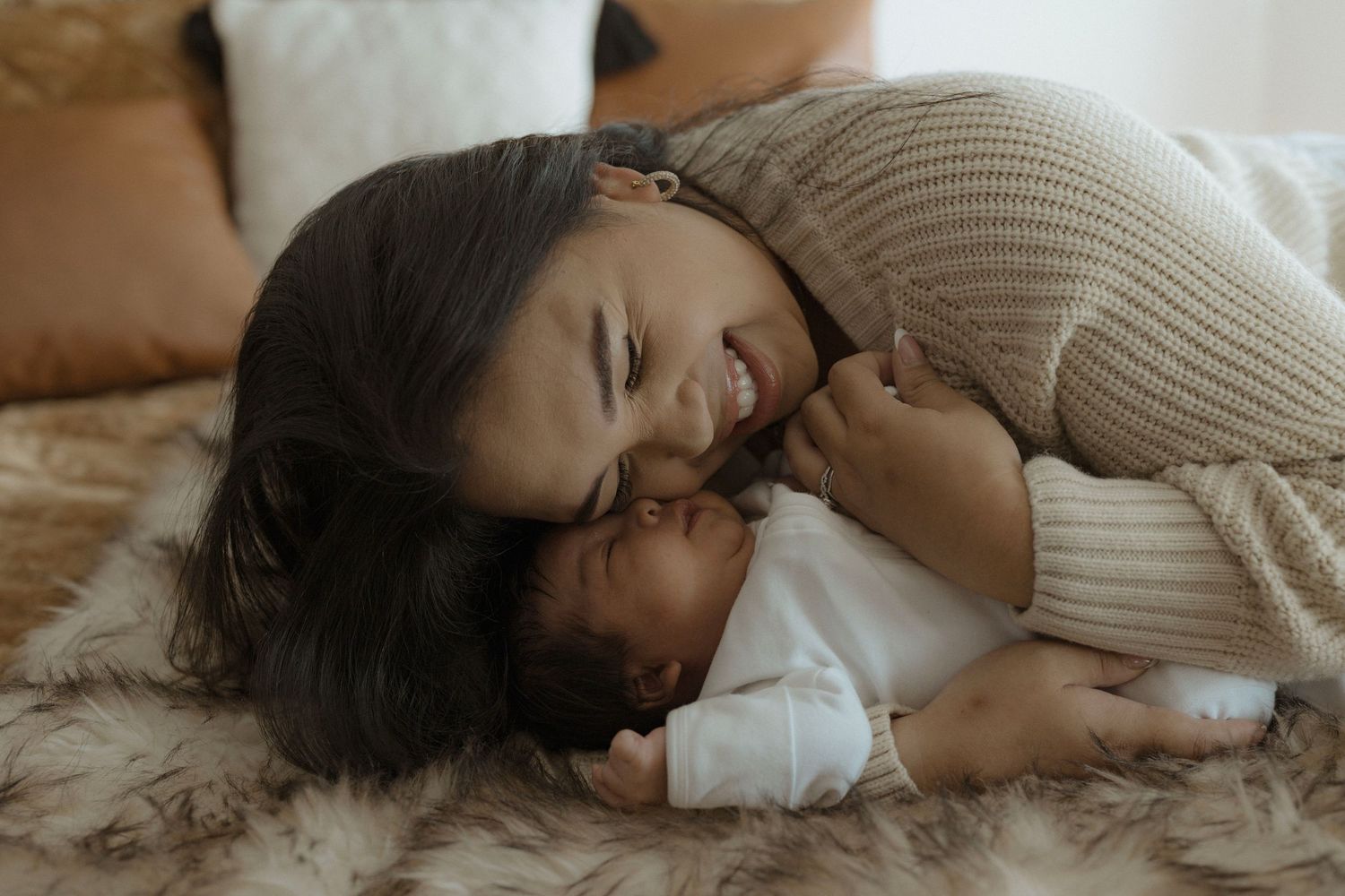 Intimate newborn photo of mother and baby on the bed in their home.