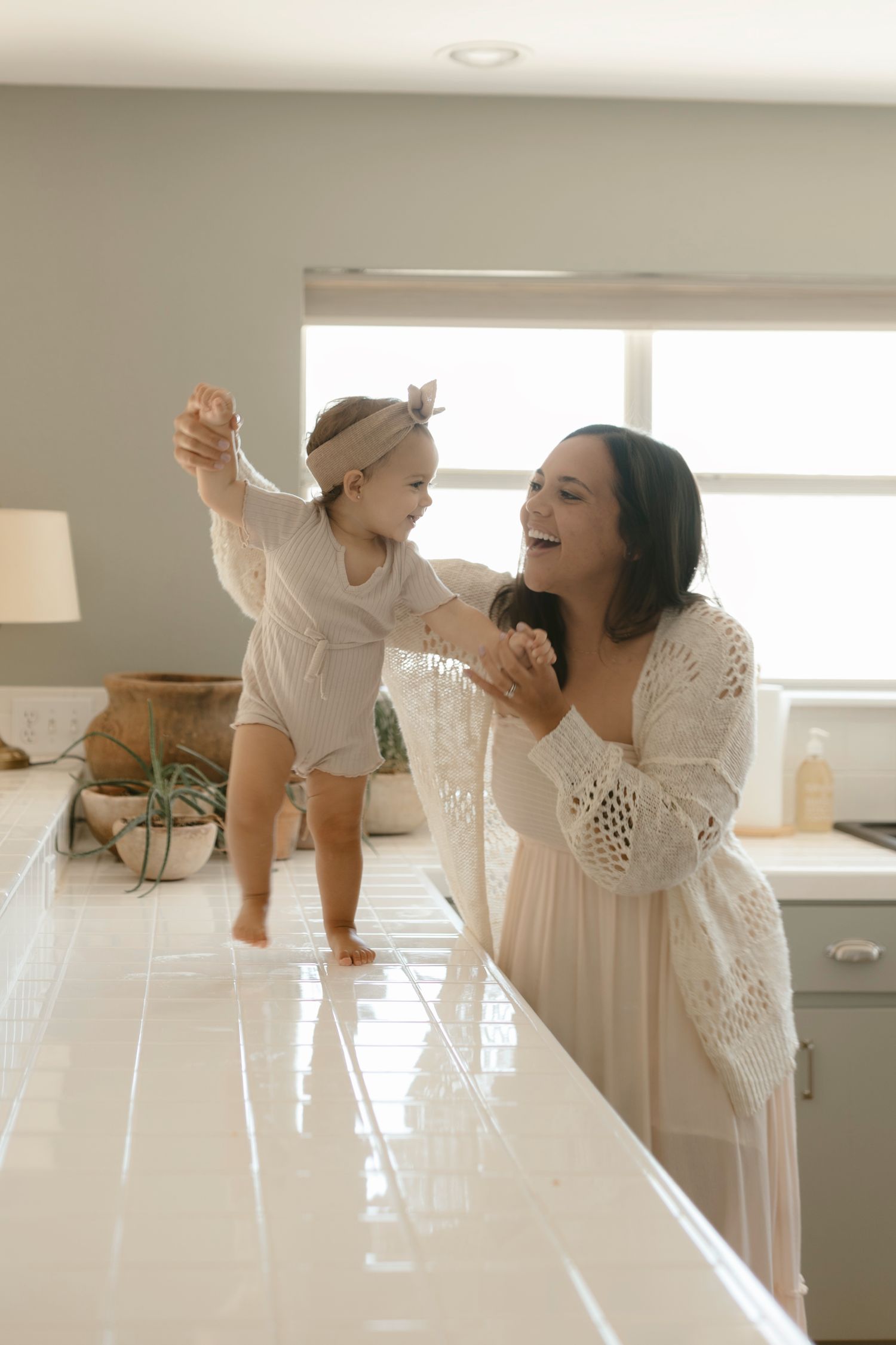 Joyful family photos in the Georgetown/Austin area on a bright kitchen counter with parent and child in white attire.