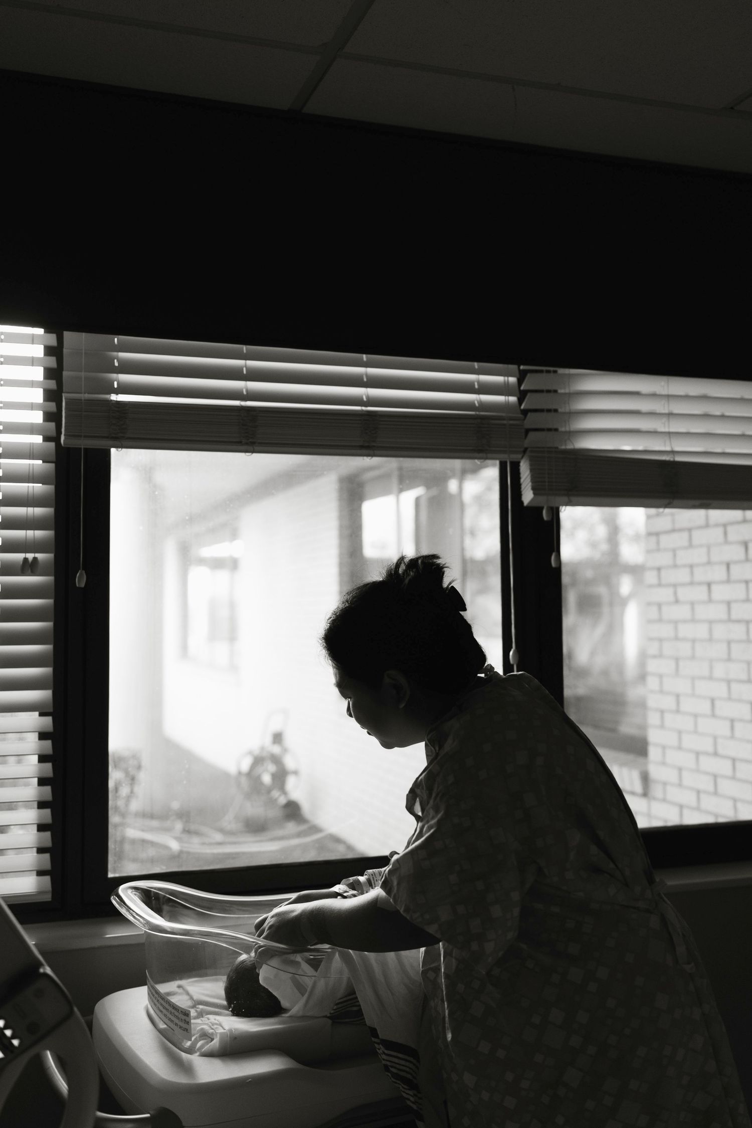 Dark silhouettes in a hospital room, mom attending to baby