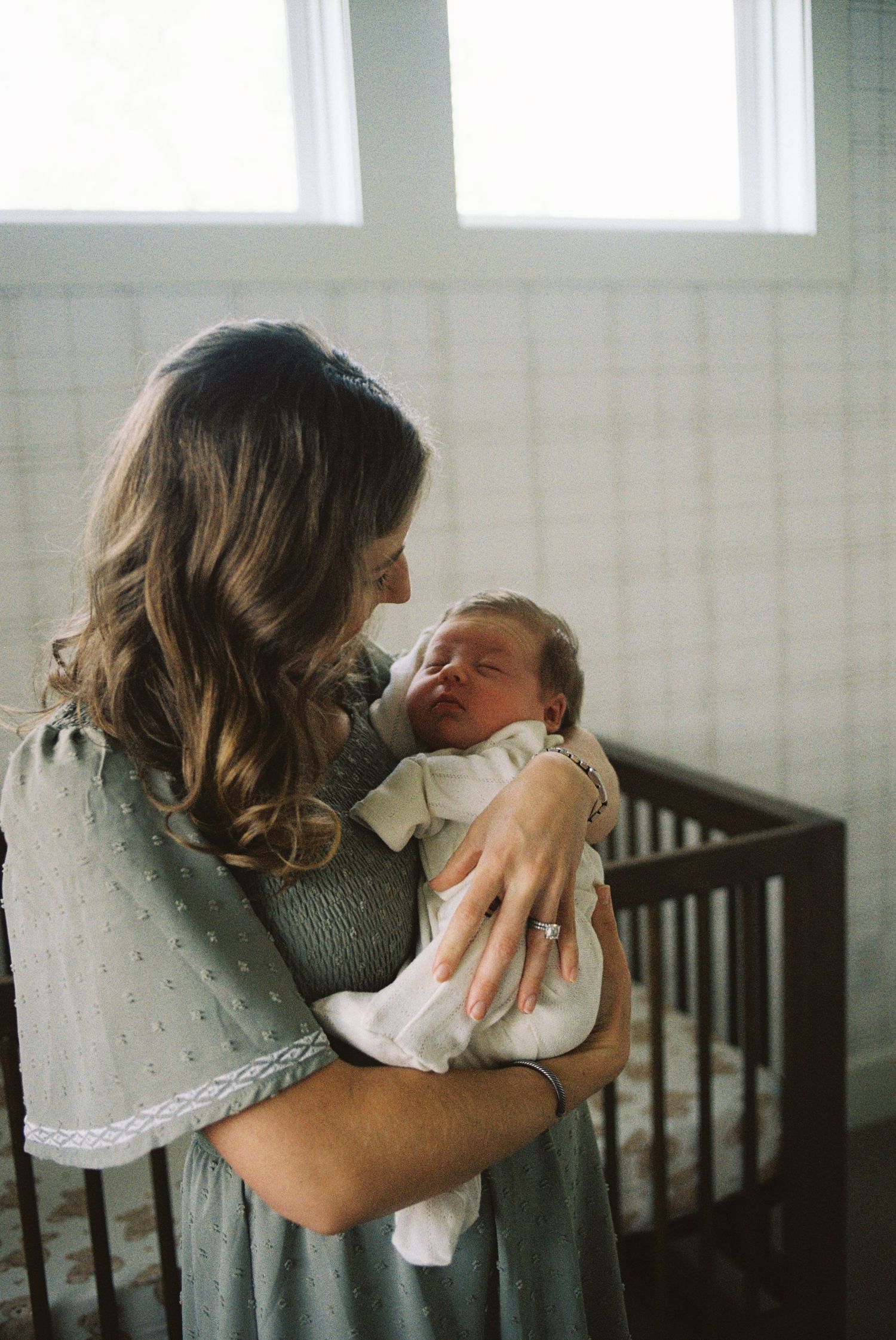 A series of four tender moments showing a caregiver comforting and holding a baby in a softly lit nursery.