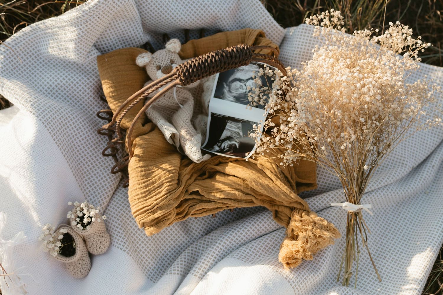 Vintage photographs and dried baby's breath flowers arranged on mustard yellow fabric with white textile backdrop.