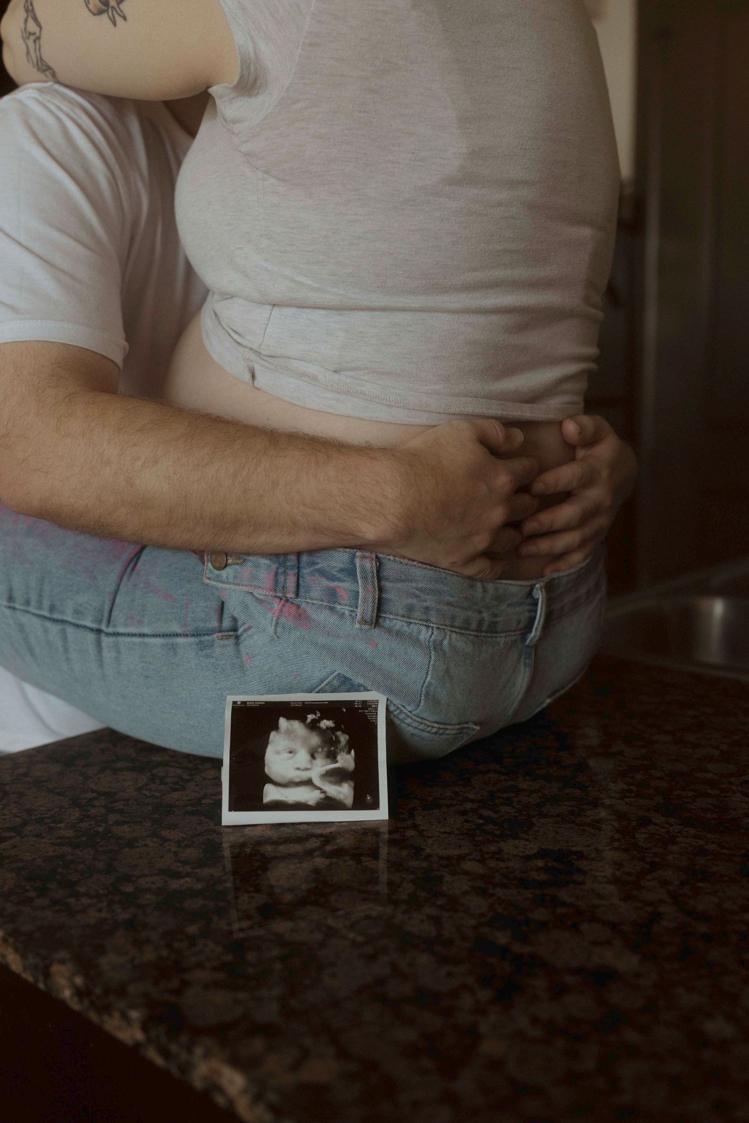 Close-up of a couple with an ultrasound photo placed on a dark countertop.