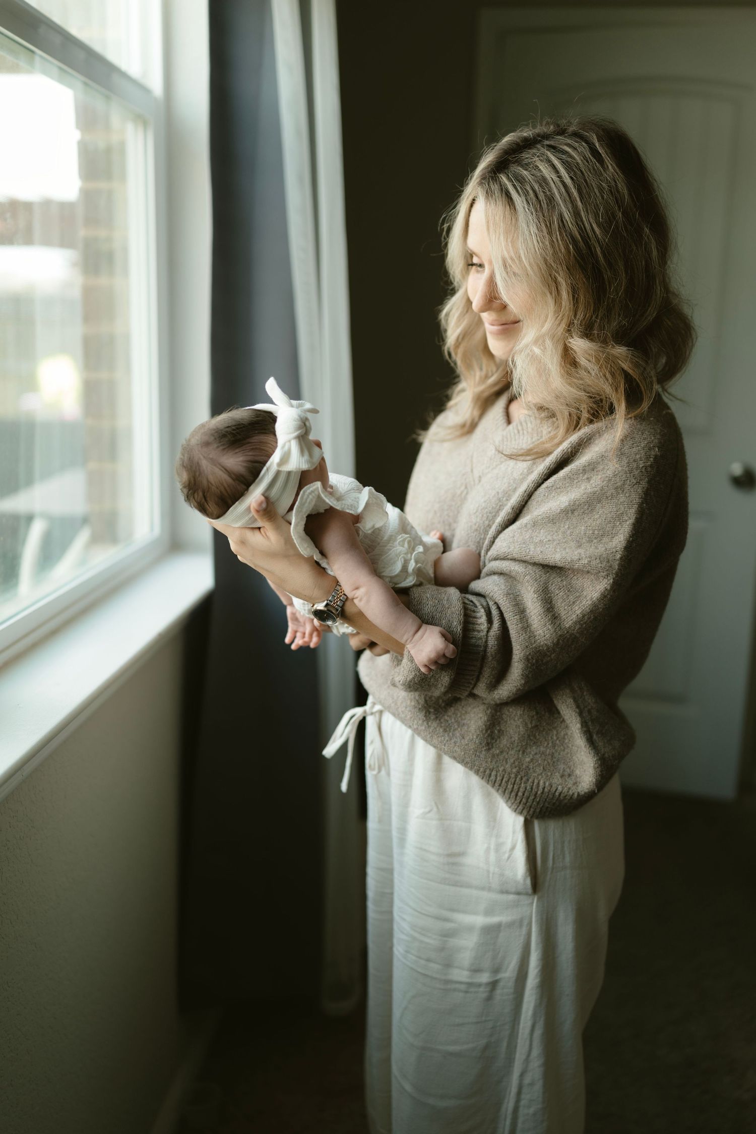 A newborn photo of a mother cradling a newborn baby while looking on adoringly.