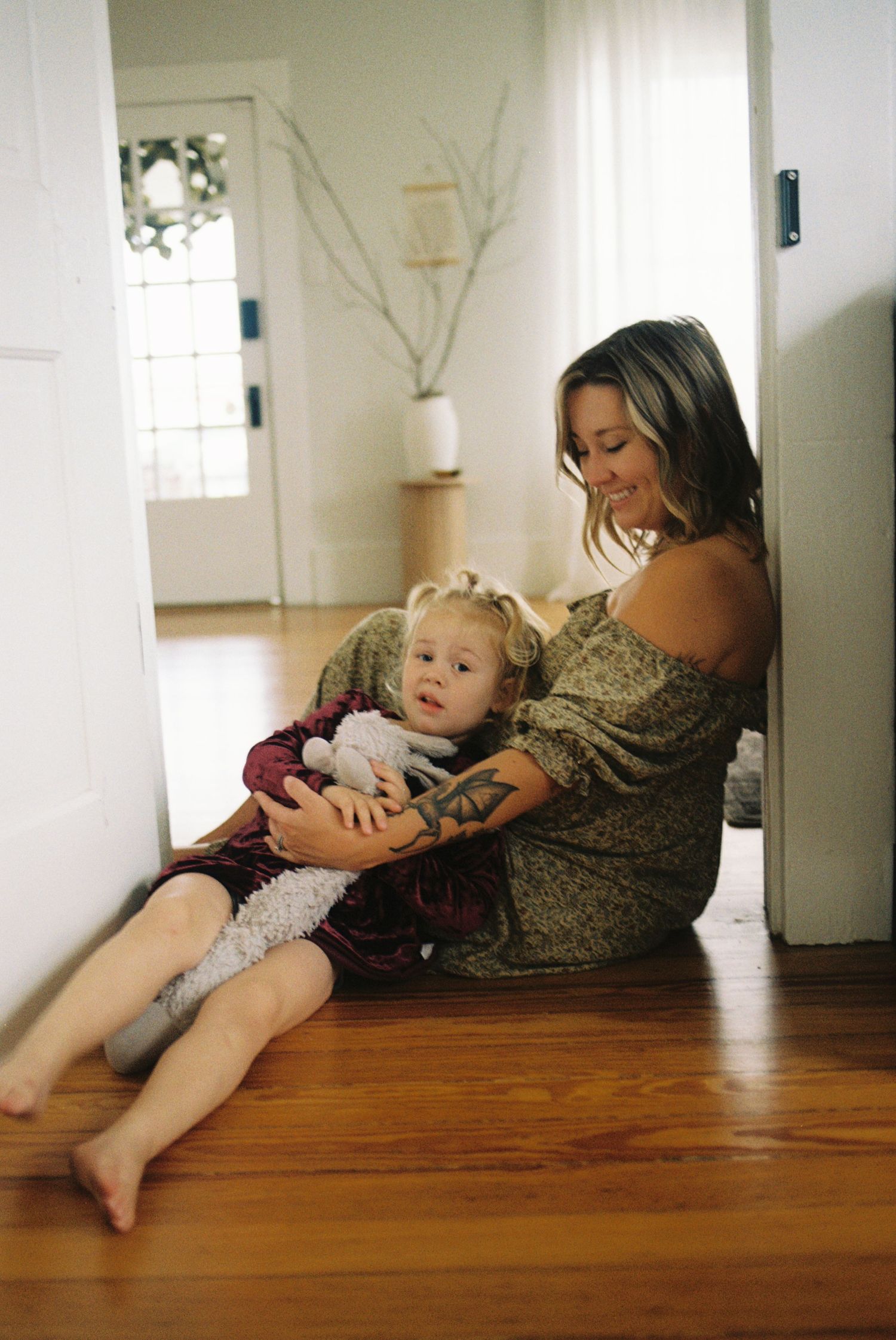 A series of candid photos showing tender moments between parent and child relaxing together on hardwood floors.
