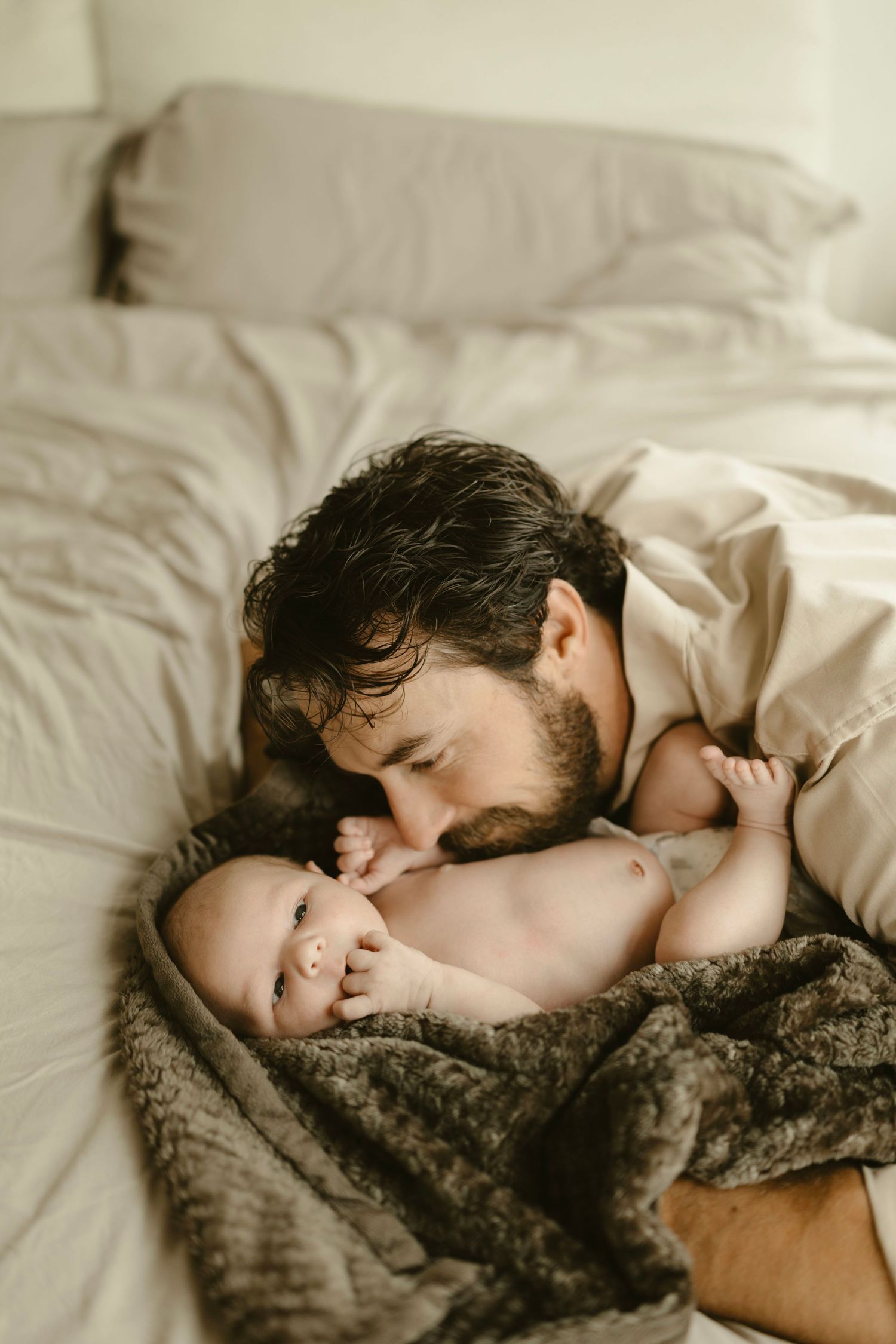 Tender moment of father bonding with a baby tucked under a cozy blanket.
