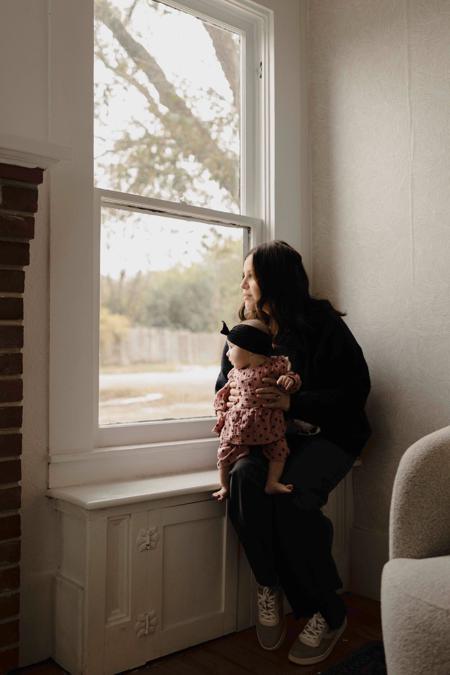 A series of four photos showing a person and child looking out a bright window in a minimalist white room.