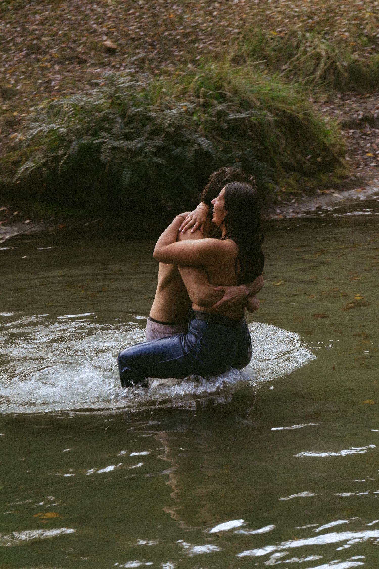 Romantic couple embraces in a flowing river surrounded by nature.