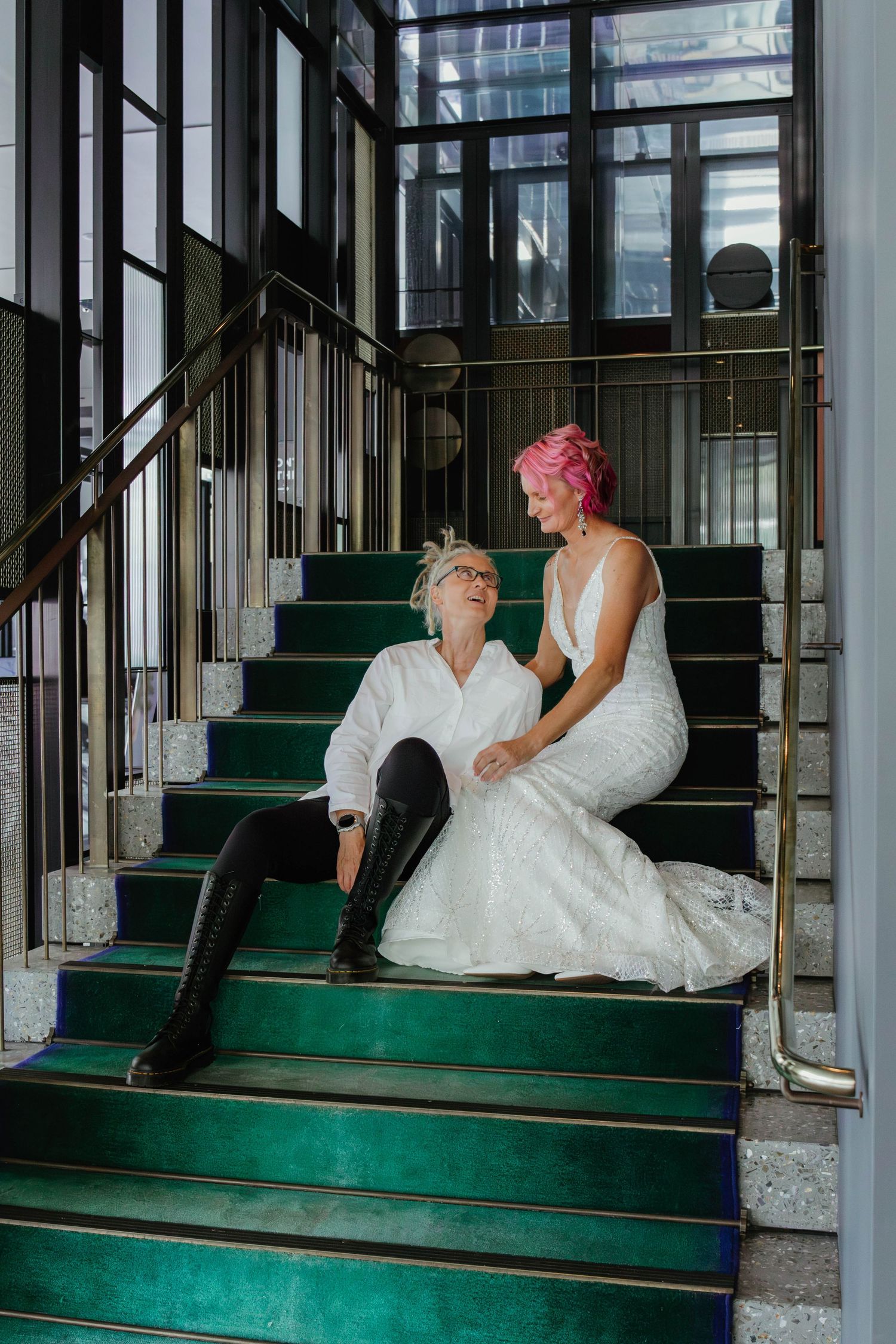Wives sit on an emerald green stair case.
