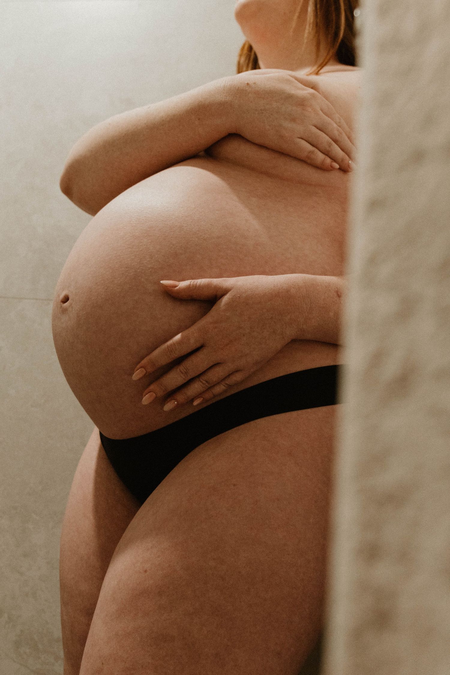 Peaking behind a towel at a pregnant woman's belly.