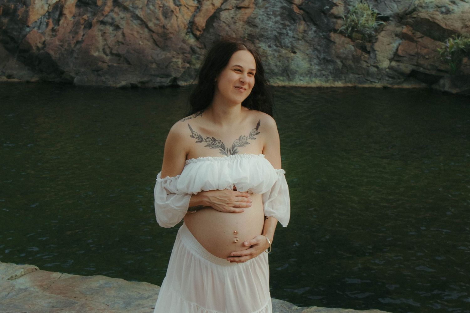 Smiling woman in a two piece set holds belly.