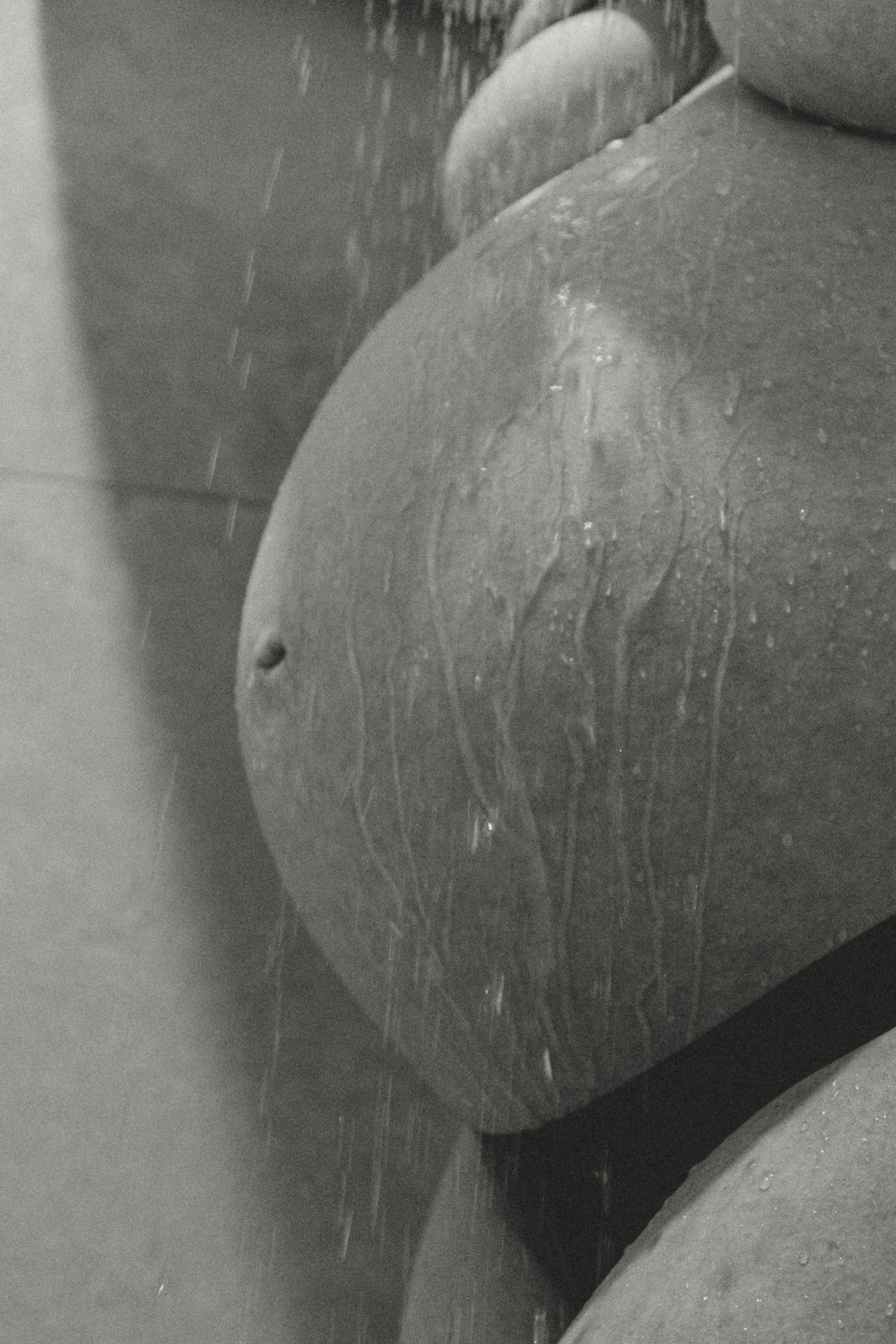 Black and white image of a pregnant belly with dripping water.