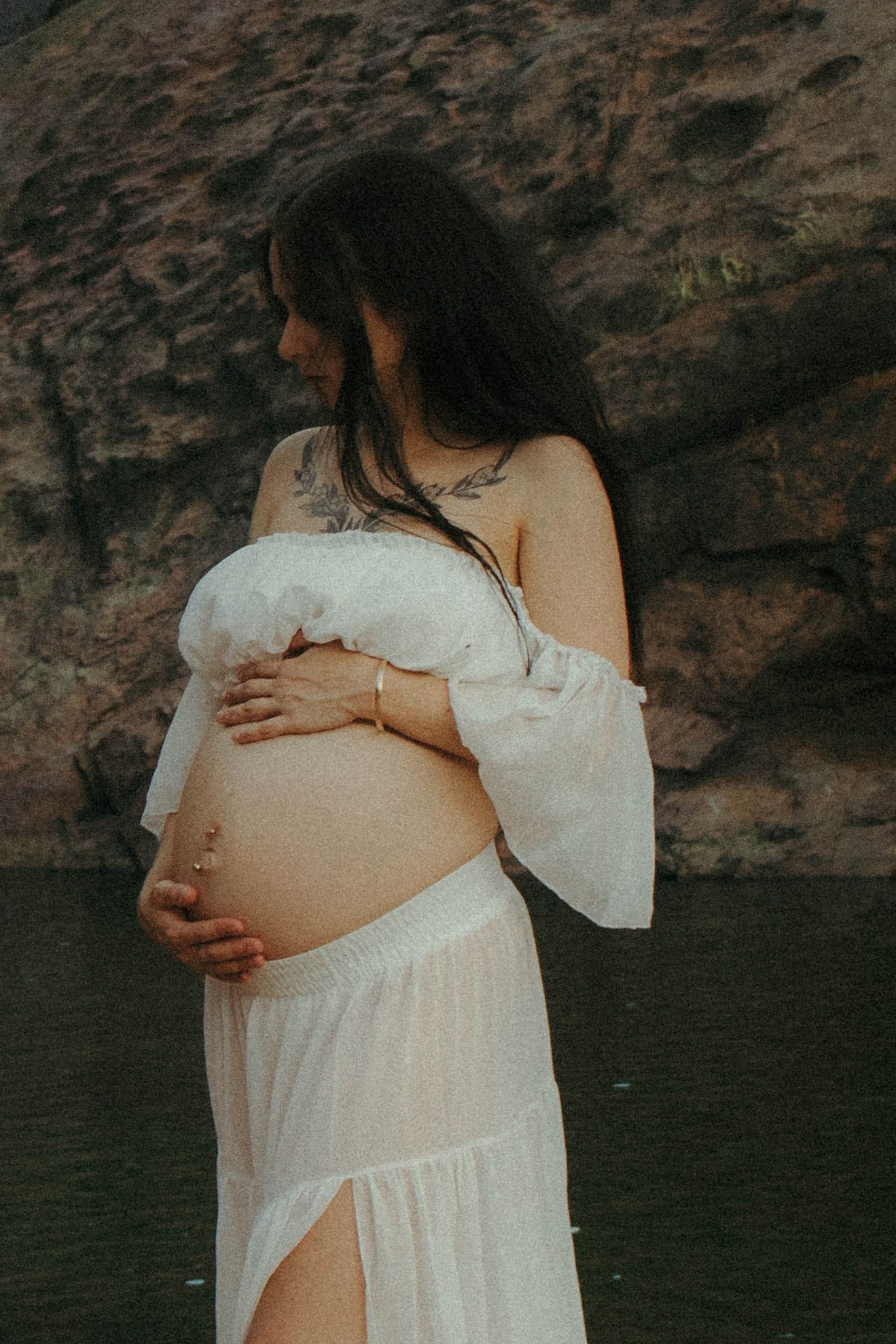 Dark haired woman caresses pregnant belly.