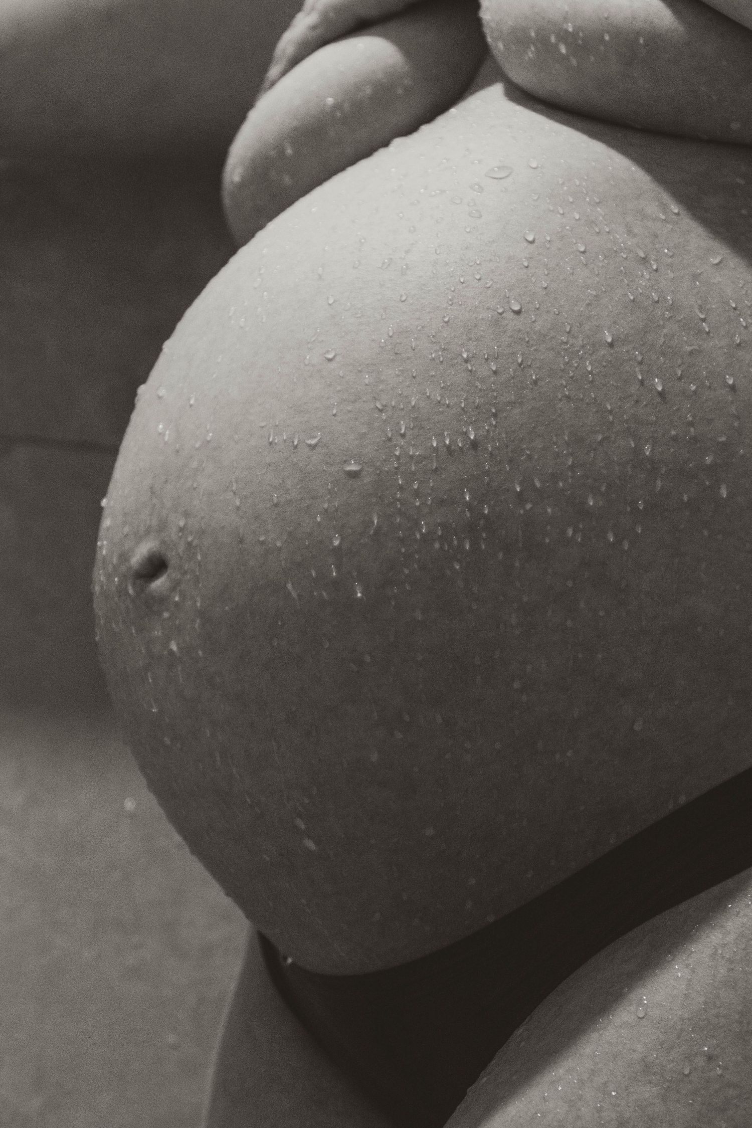 Black and white pregnant belly with water droplets.