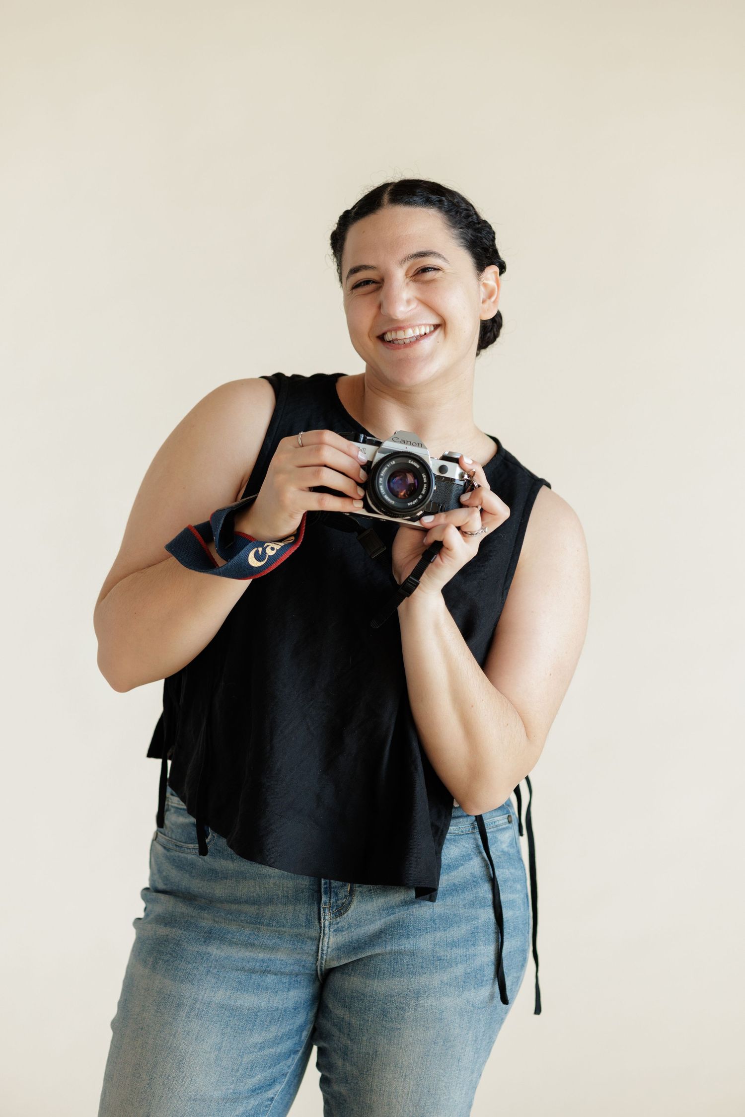 photographer holding film camera smiling at camera.