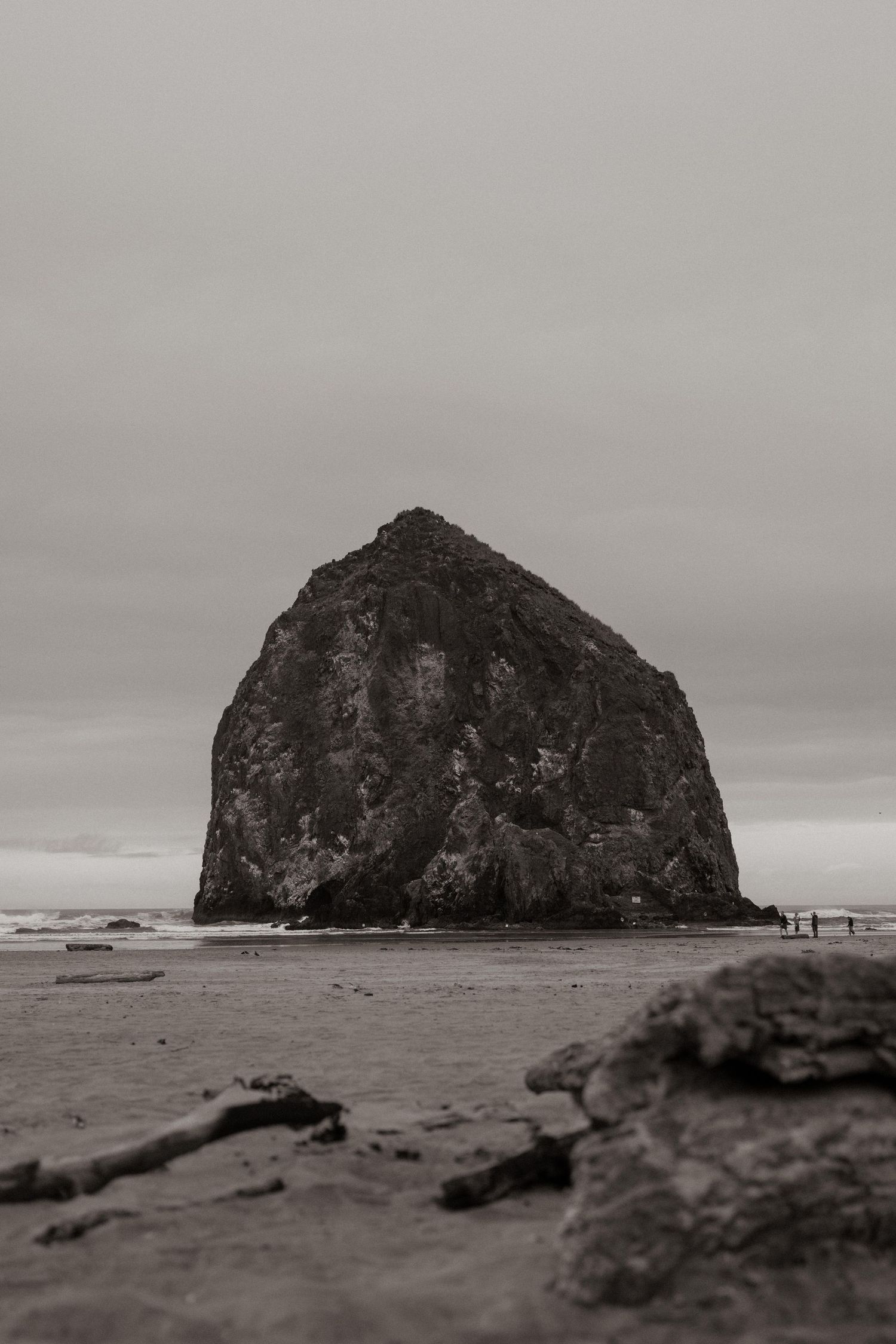 Haystack Rock at Cannon Beach, Oregon, captured in moody black and white tones under overcast skies.