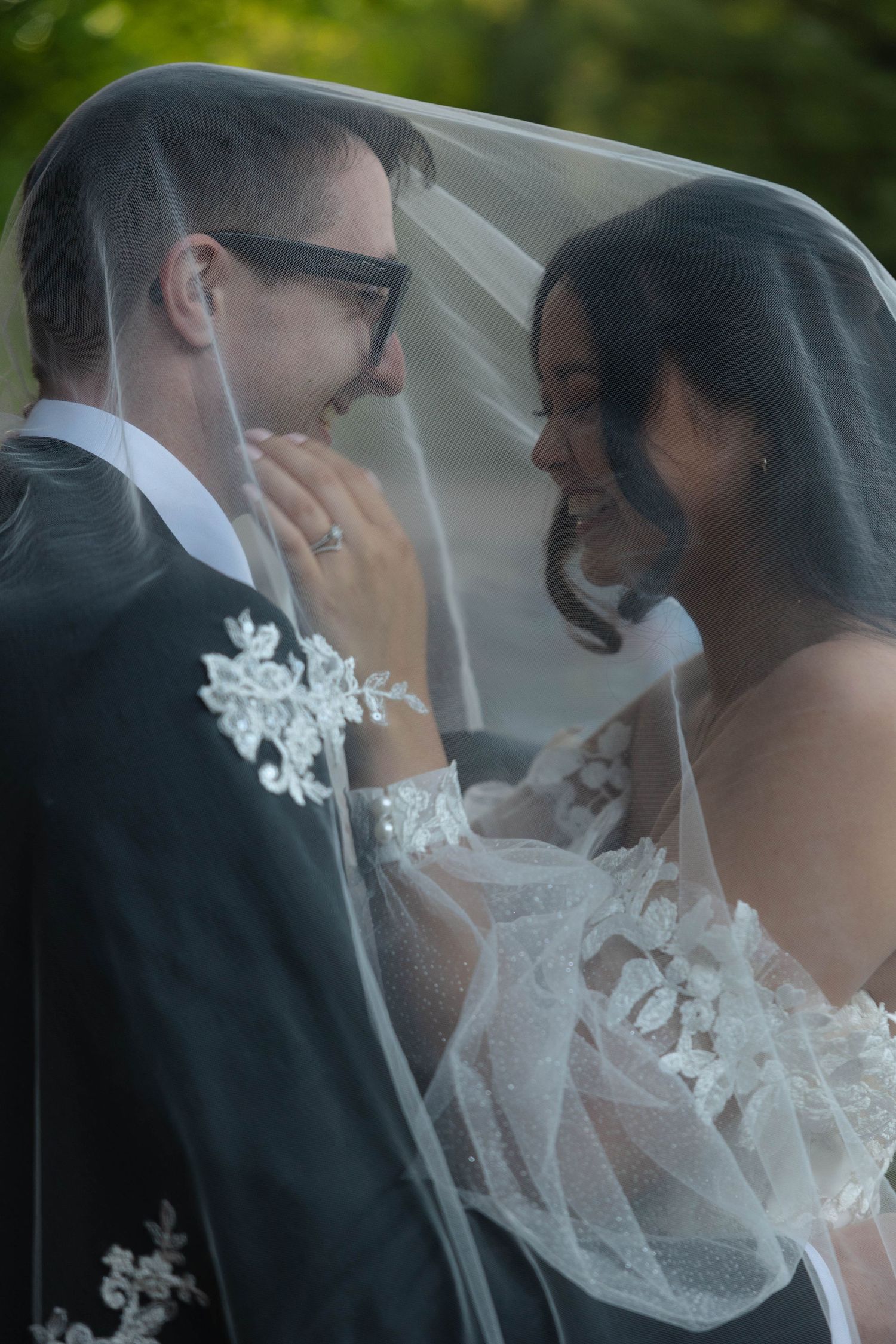 Bride and groom share a romantic moment under a wedding veil, smiling at each other in lace attire. Elopement photography angelhamidehphotos