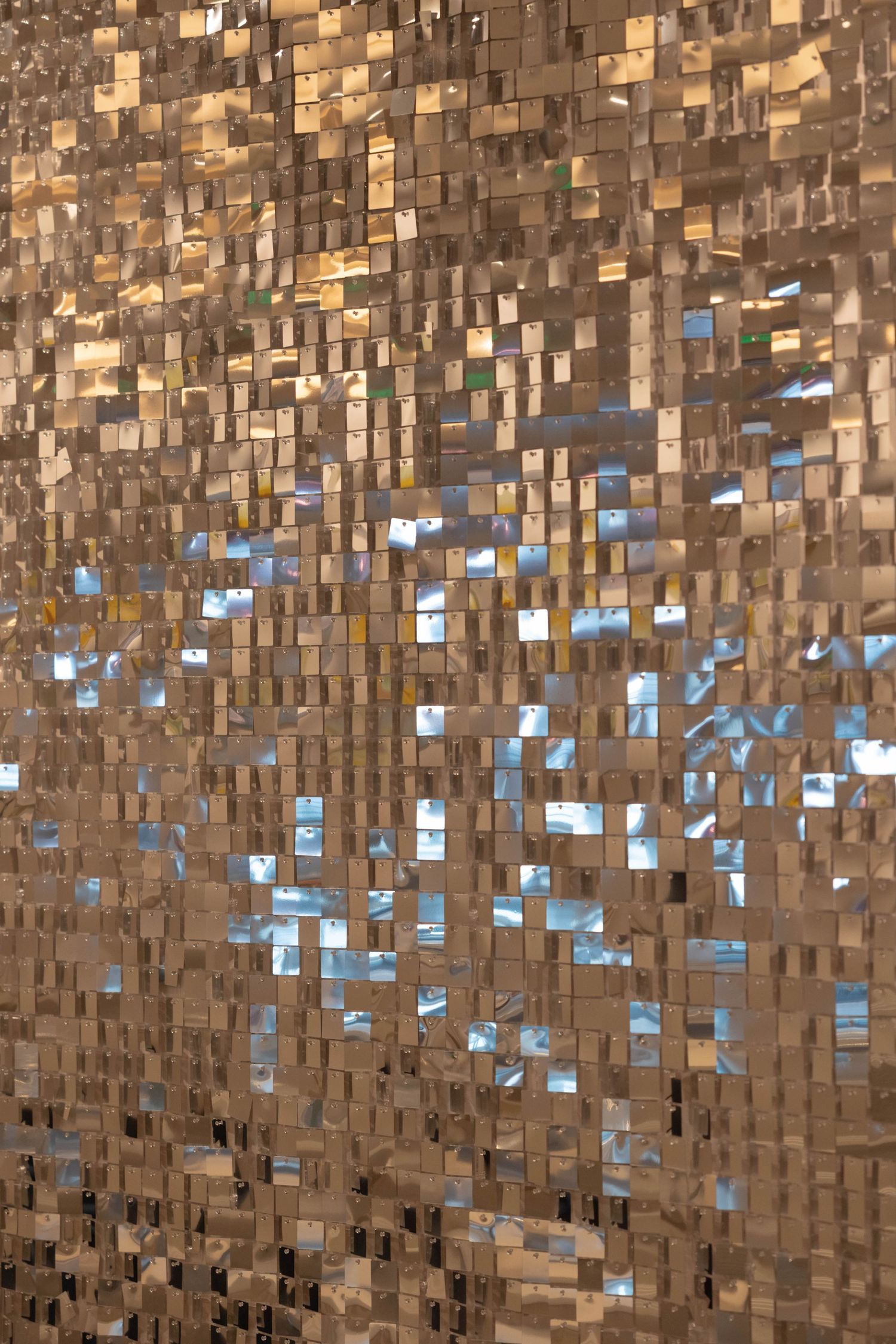 Shimmering gold mosaic wall with reflective square tiles creating a glamorous disco-inspired metallic texture background.