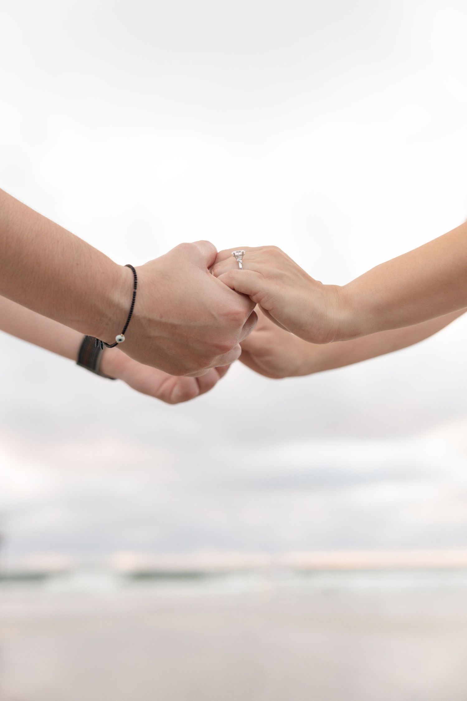 Close up of couple holding hands at the beach.