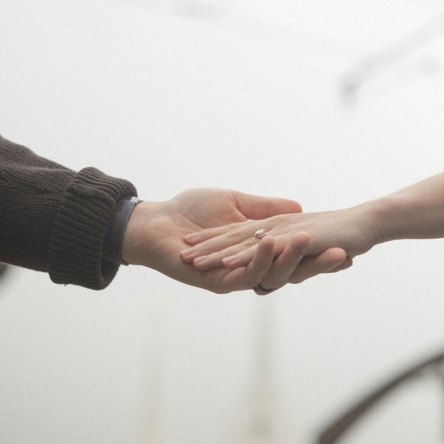 couple holding hands in the rain, close up of hands showing engagement ring.