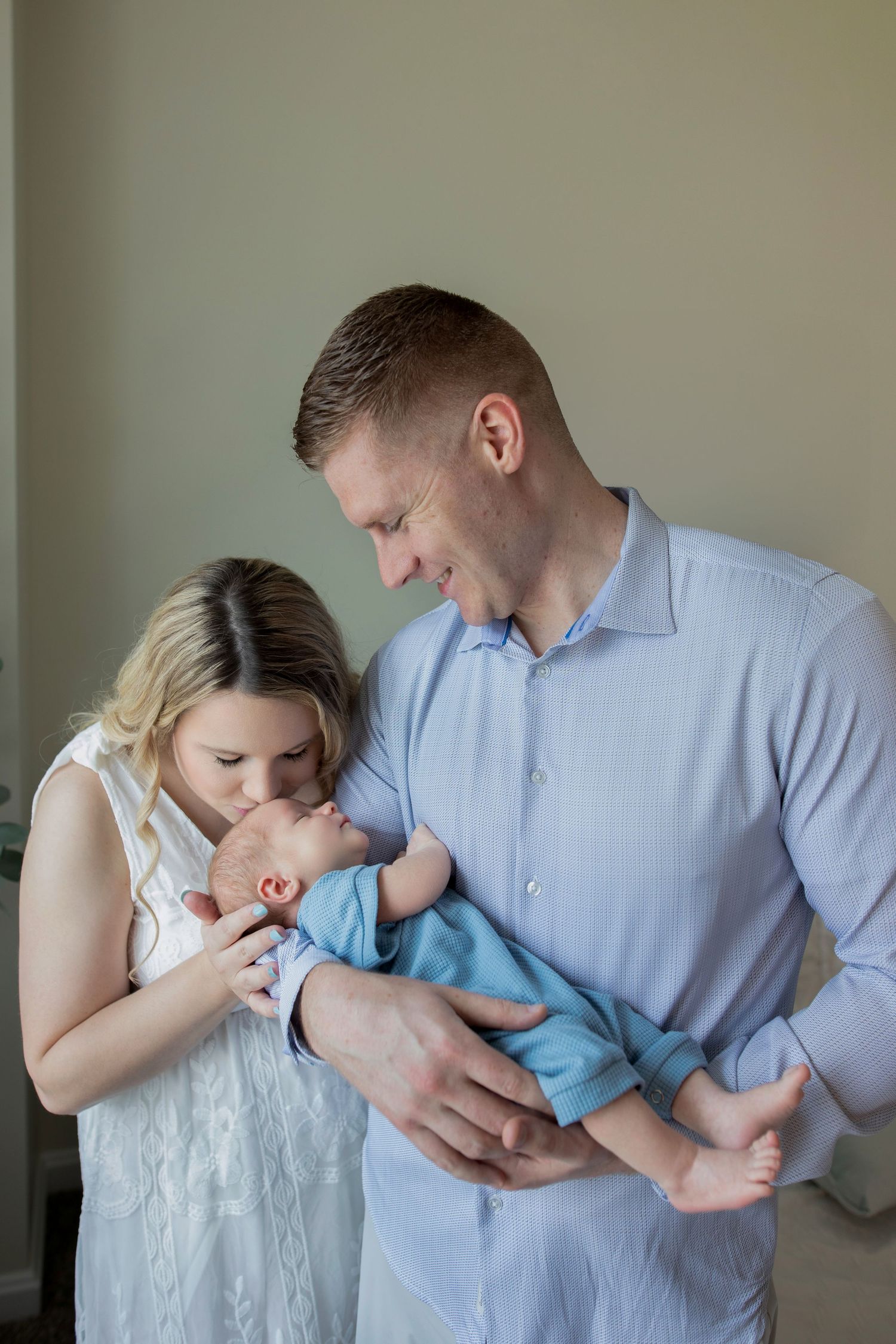 A series of tender moments between a parent in a blue shirt and a small child in white against a neutral wall background.