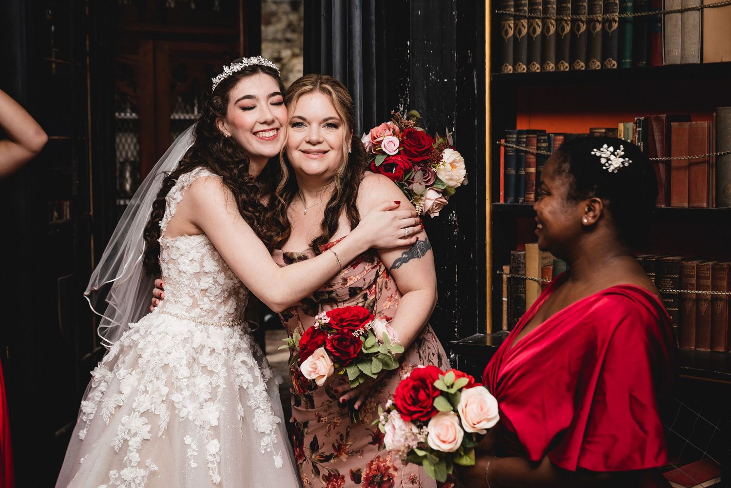 A bridal party celebrates at an elegant indoor venue with red and white roses and formal attire.