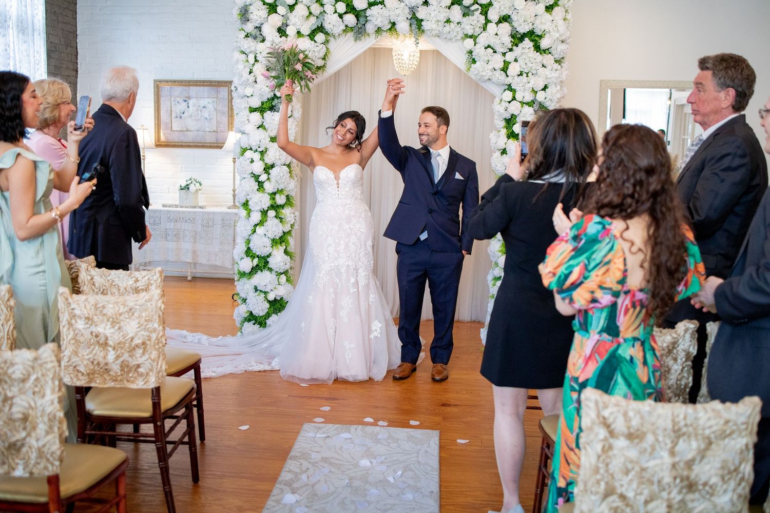A wedding reception moment with guests cheering and celebrating while the couple shares their first dance.