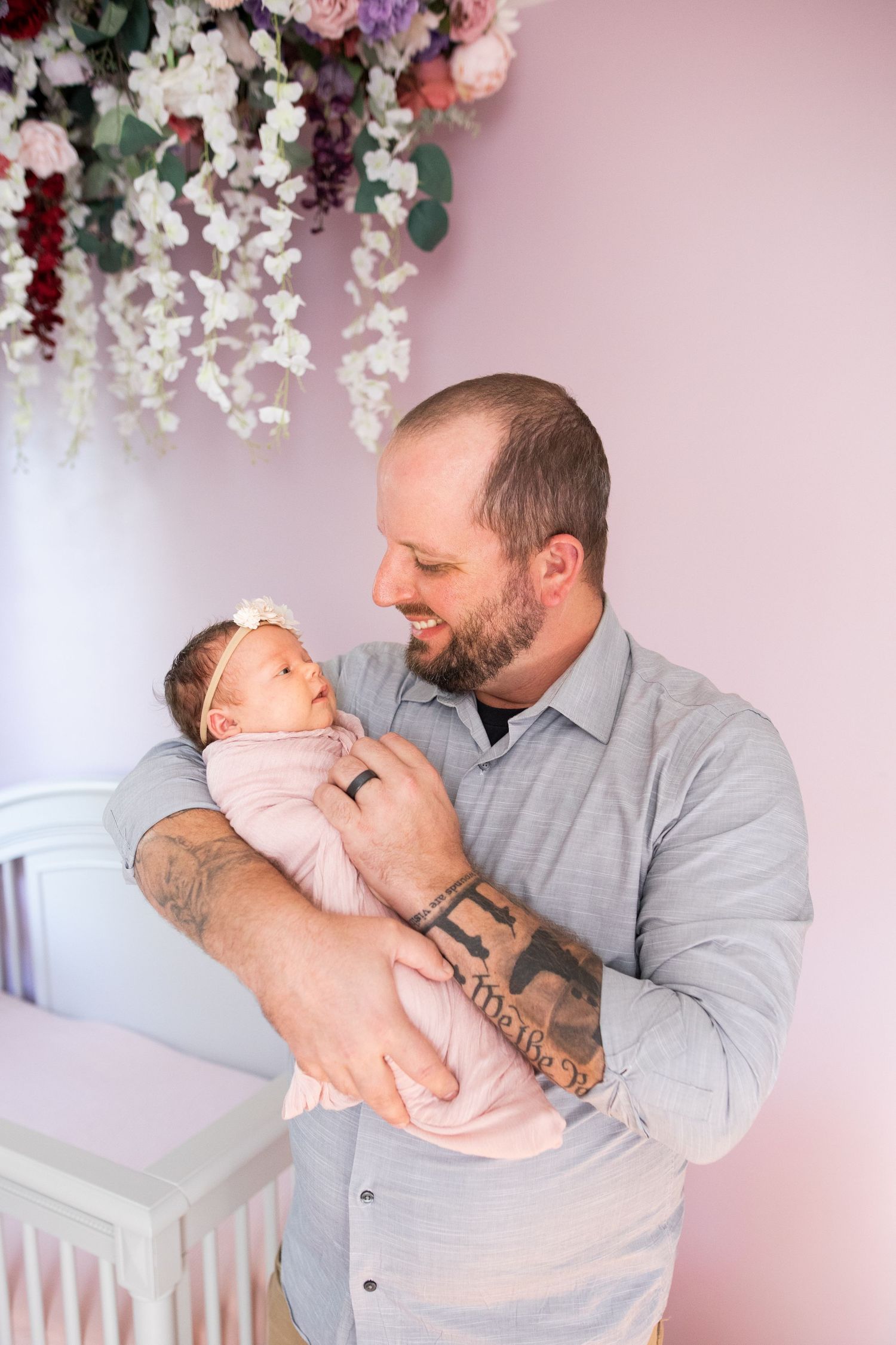 A tender moment between parent and newborn baby in a nursery decorated with hanging floral arrangements.