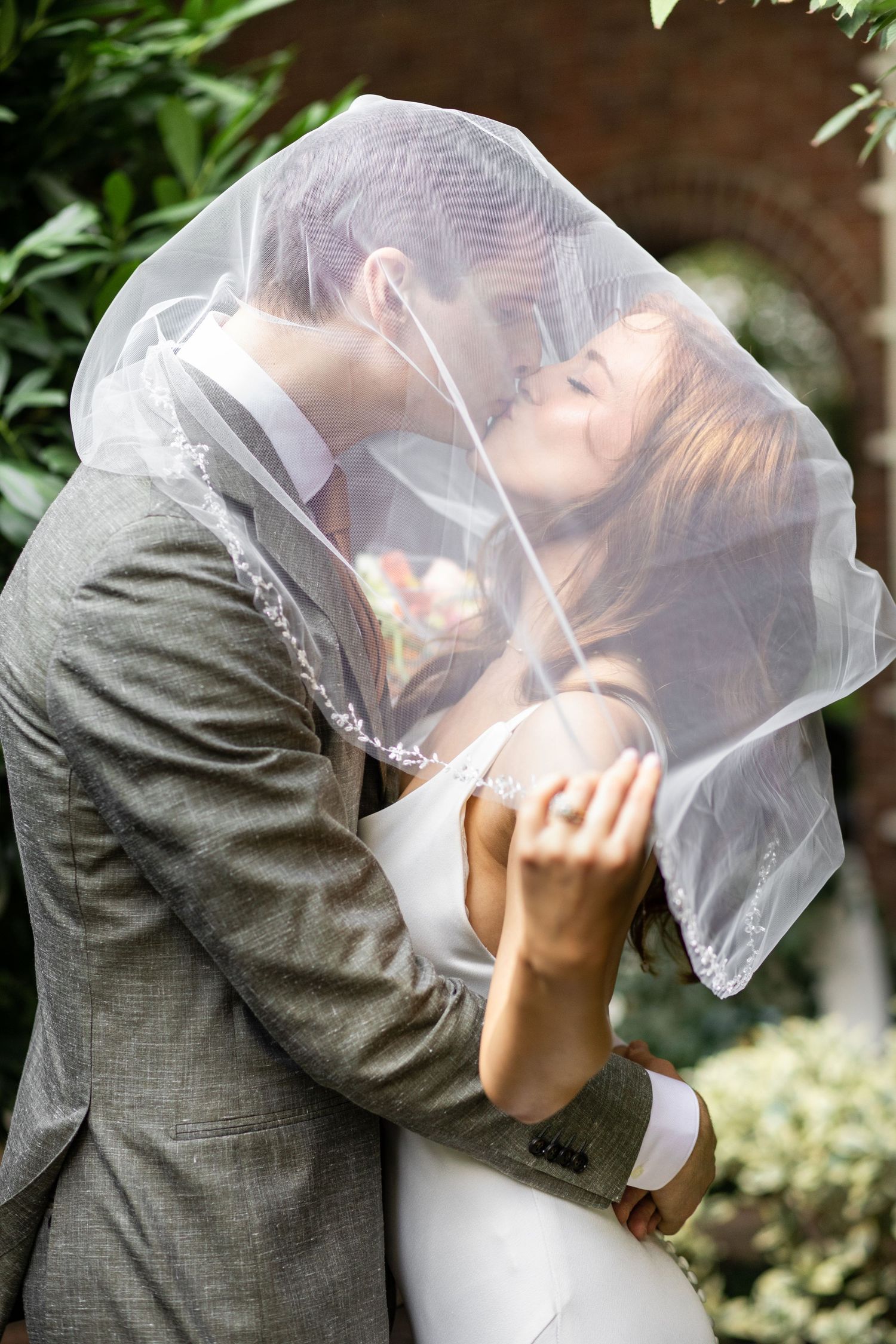 Intimate wedding portrait under flowing veil in lush garden setting during wedding at-the-morris-house-hotel in Philadelphia