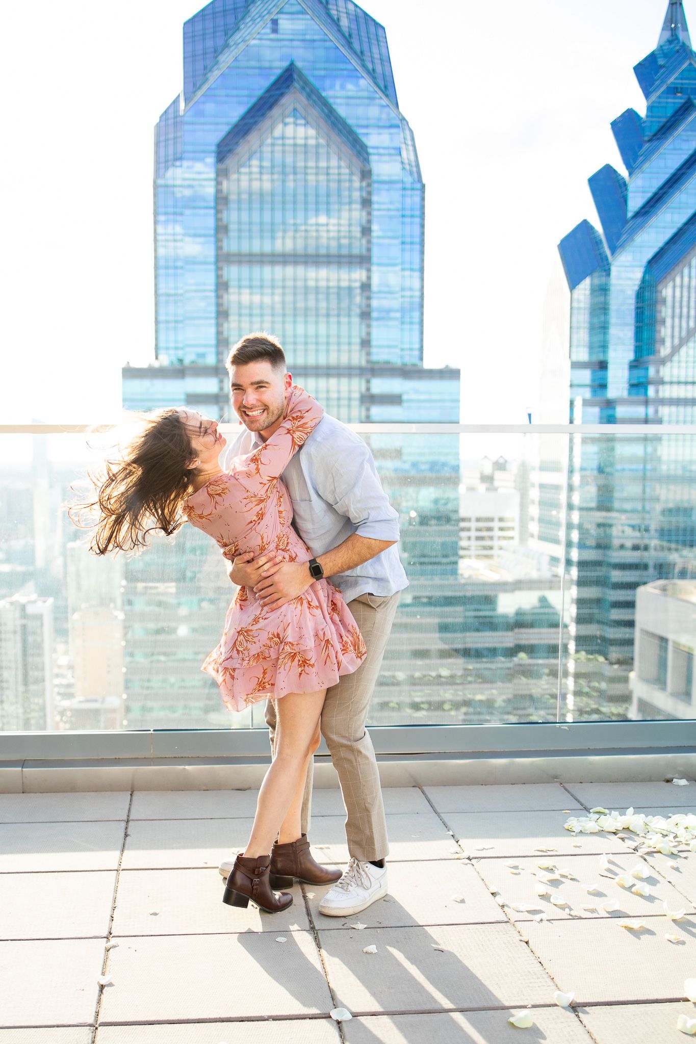 A romantic dance sequence on a rooftop terrace with glass skyscrapers in the background.