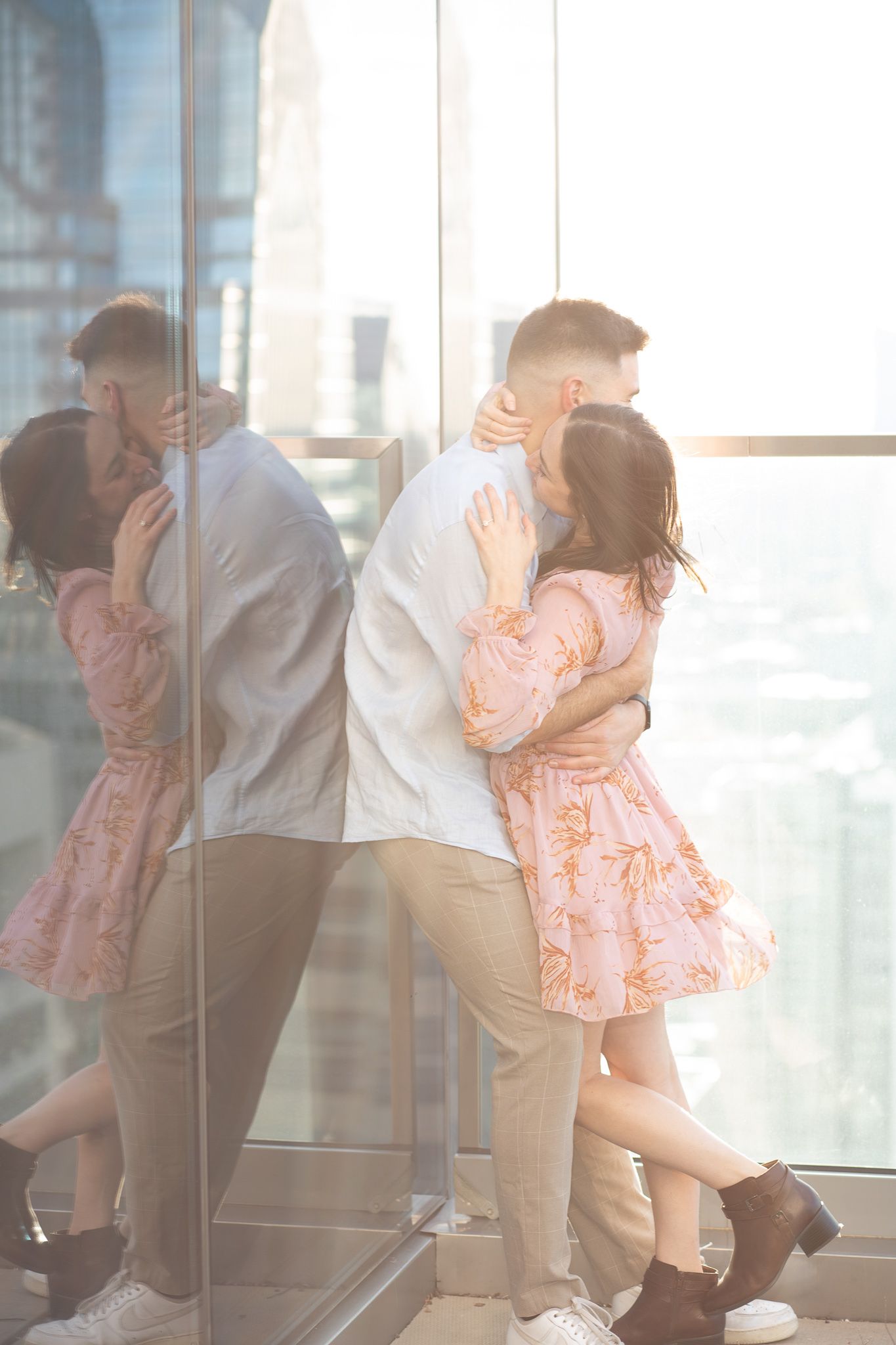 A couple in formal attire shares a romantic dance near large windows in an elegant indoor setting.