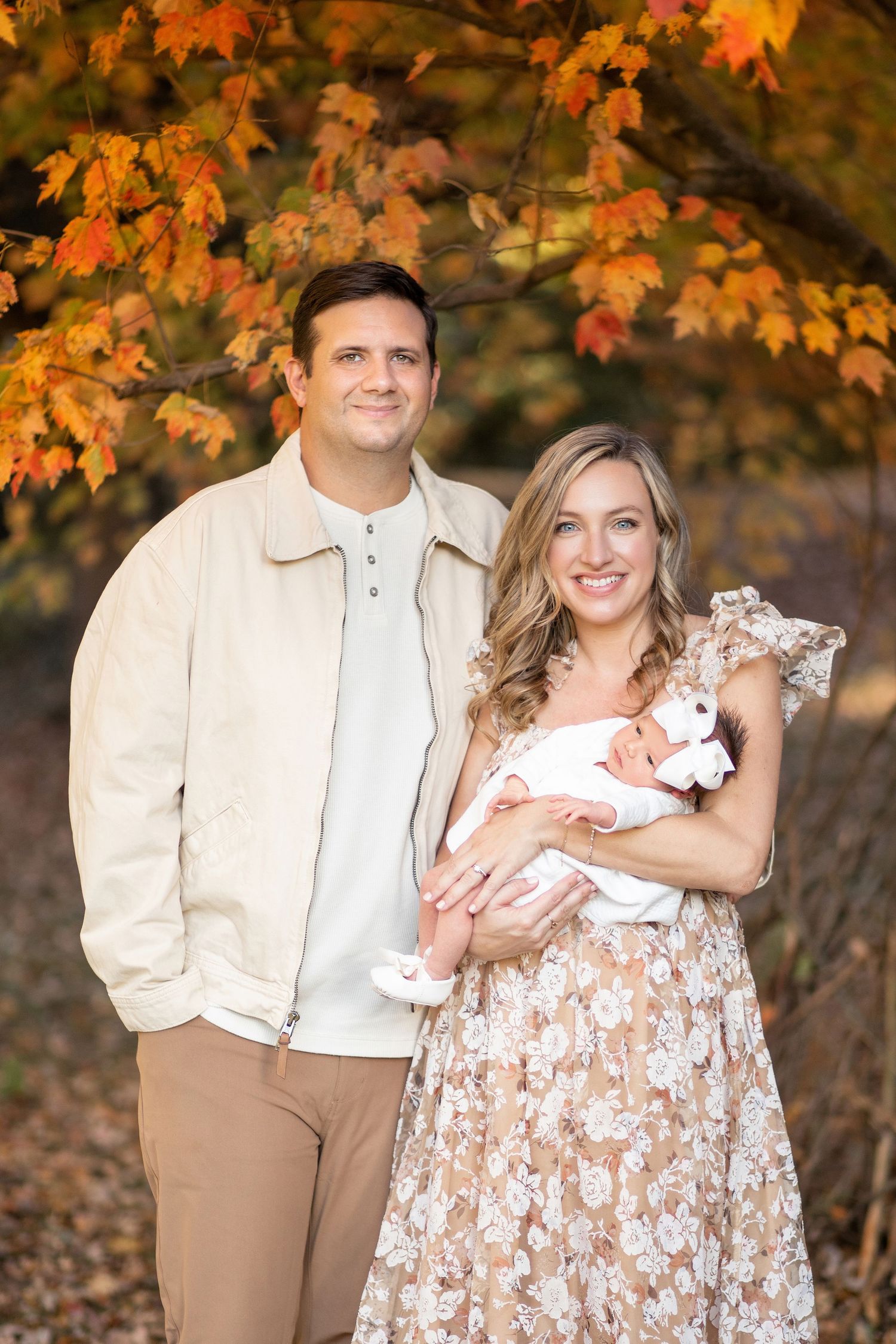 A couple stands together against a backdrop of vibrant orange autumn maple leaves during a fall photo session.