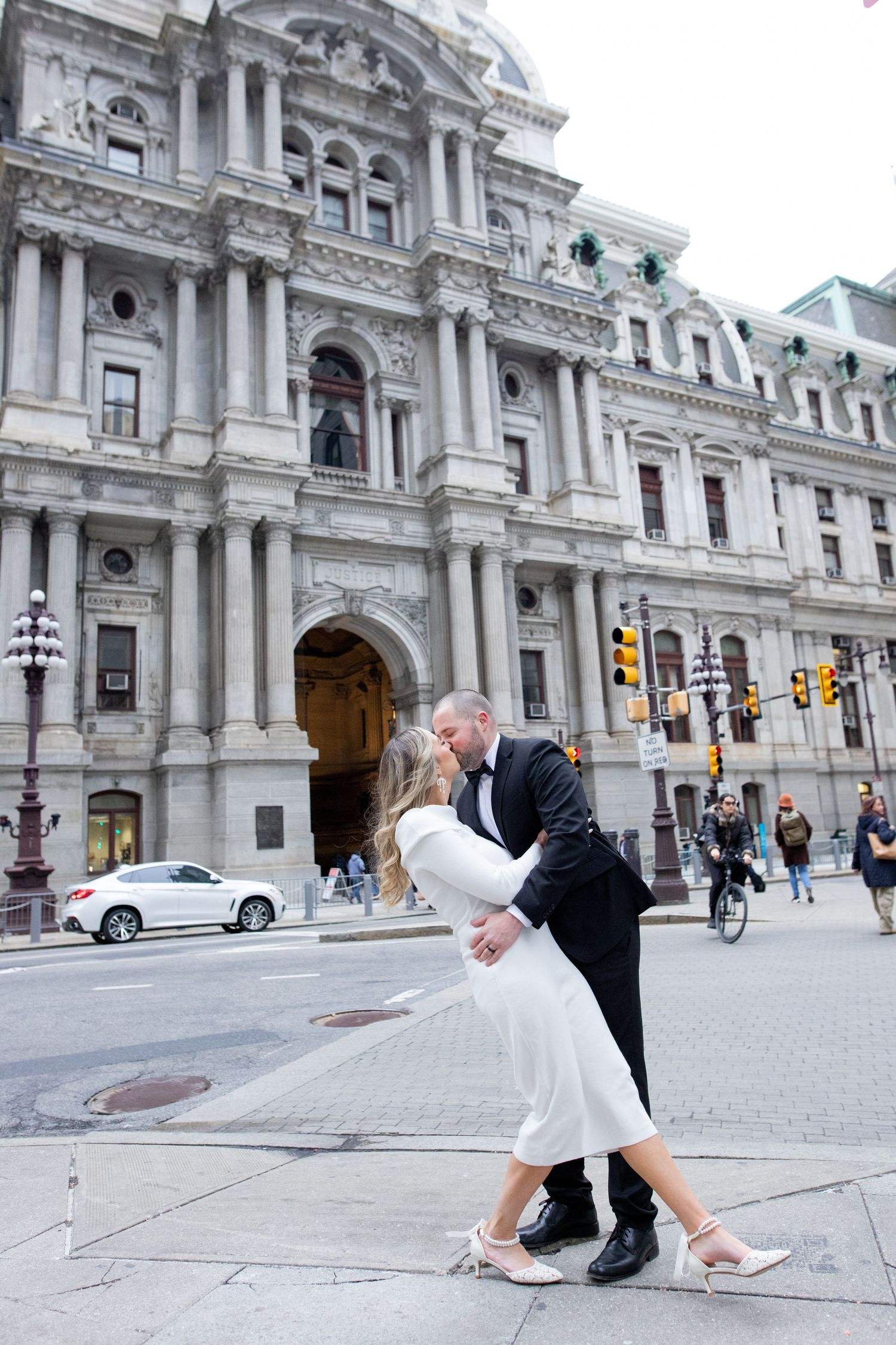 A couple dips romantically in front of the ornate Philadelphia City Hall building with classic architecture in the background.