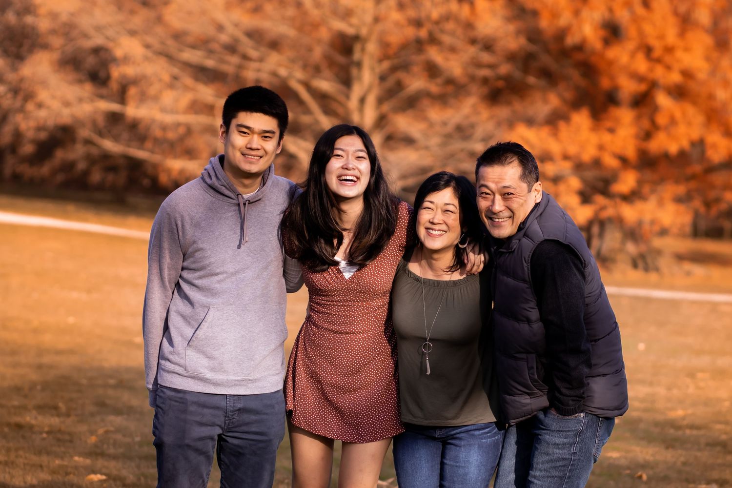 Family members posing together outdoors during golden hour with warm sunset lighting in a natural setting.
